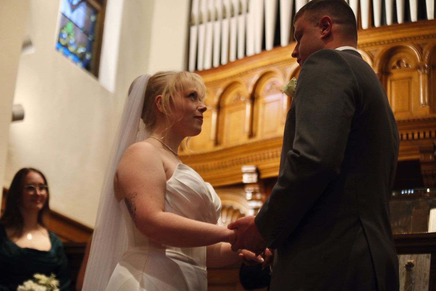 Intimate wedding ceremony moment in front of wooden church organ pipes.