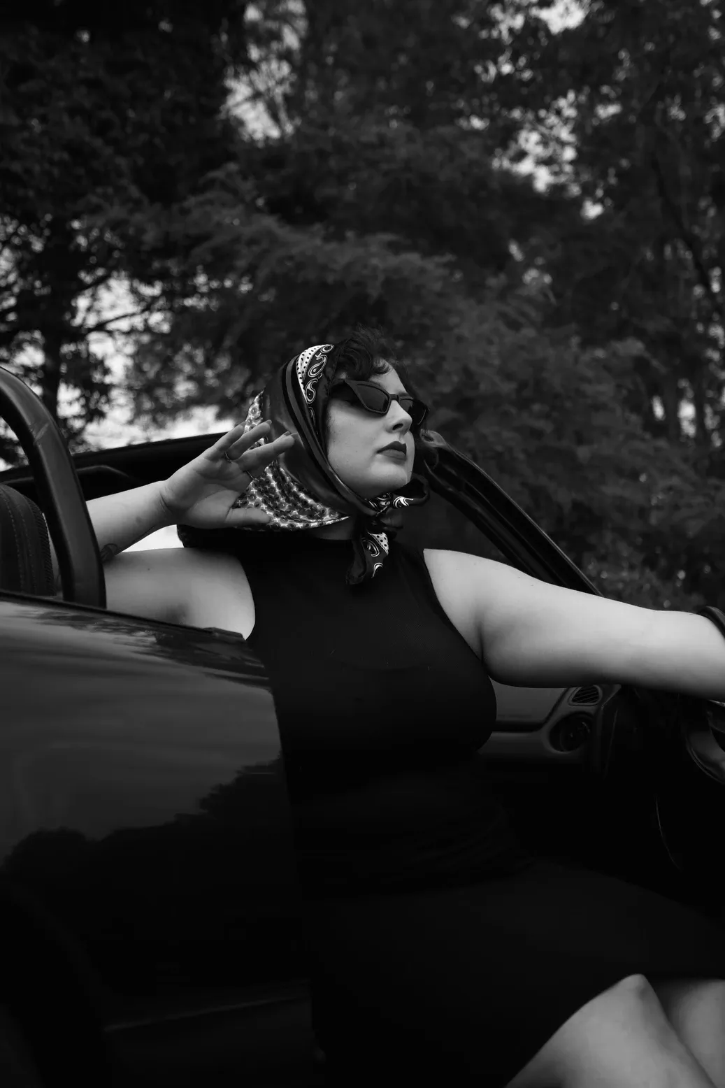 A black and white artistic photo series showing someone reclining across a car hood in a dramatic pose.