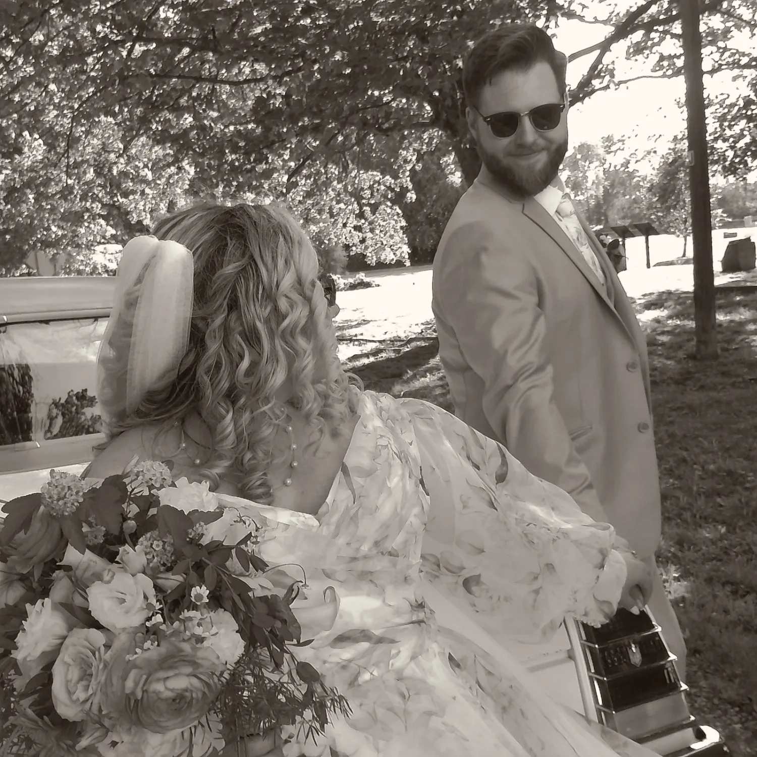 Bride in flowing dress and groom share candid moments outdoors.