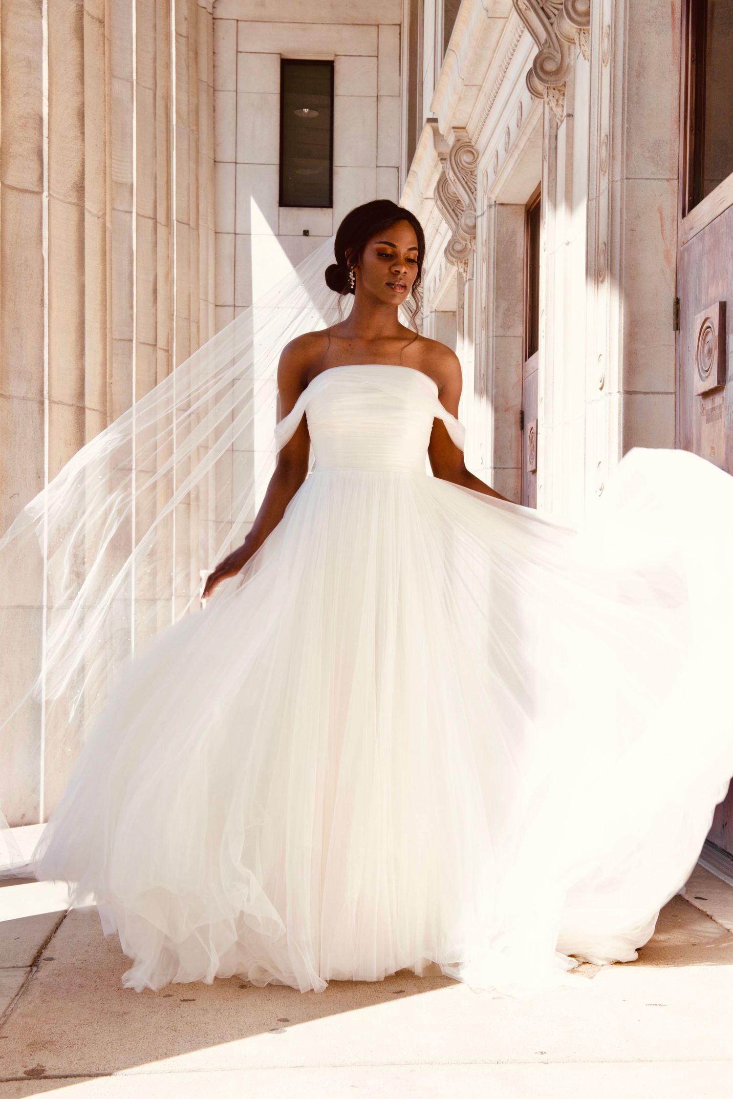 Flowing white wedding dress twirling in an elegant hallway with classical columns.