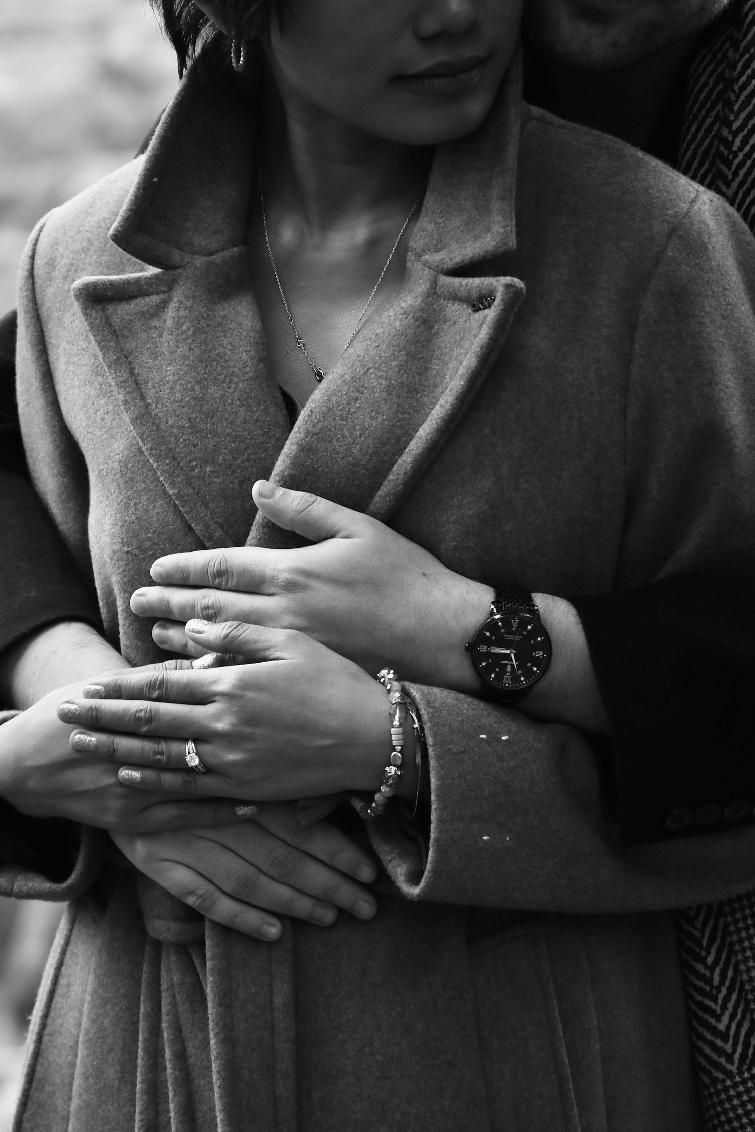 Close-up black and white shot of hands wearing engagement rings.