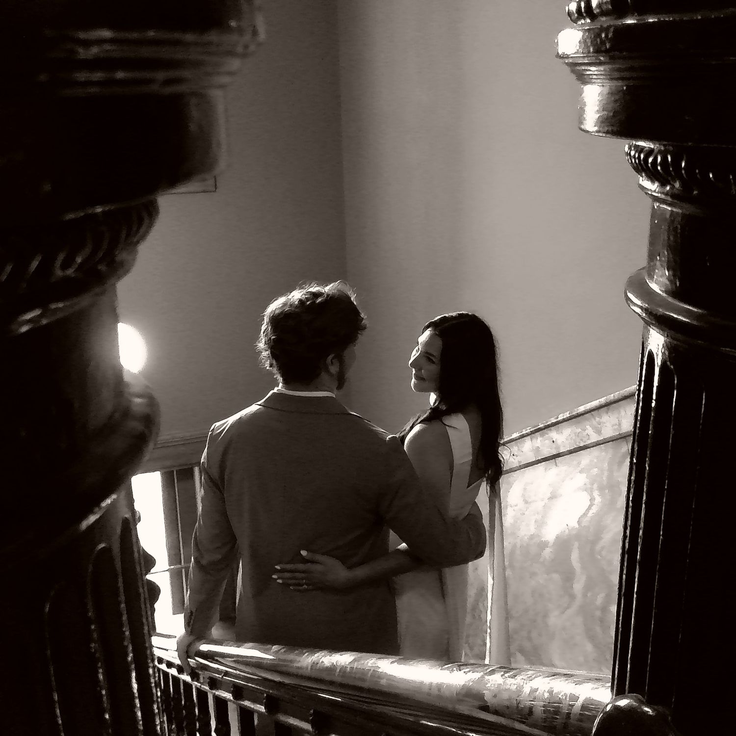 Romantic silhouettes against a softly lit stairwell with classic architectural details.