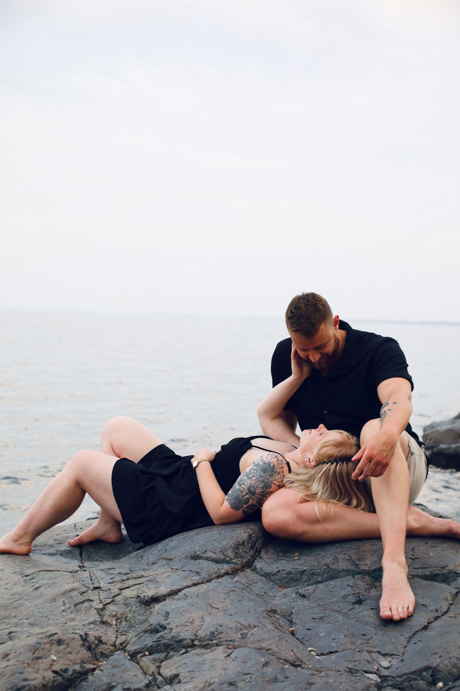 Intimate couple's portrait session on rocky beach landscape.