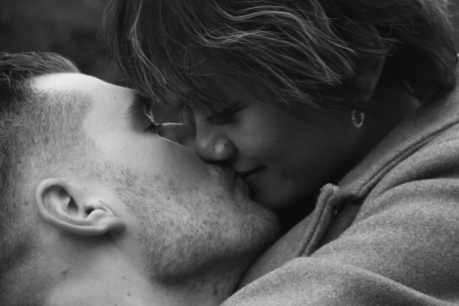 A romantic black and white close-up photo of a tender kiss between two people.