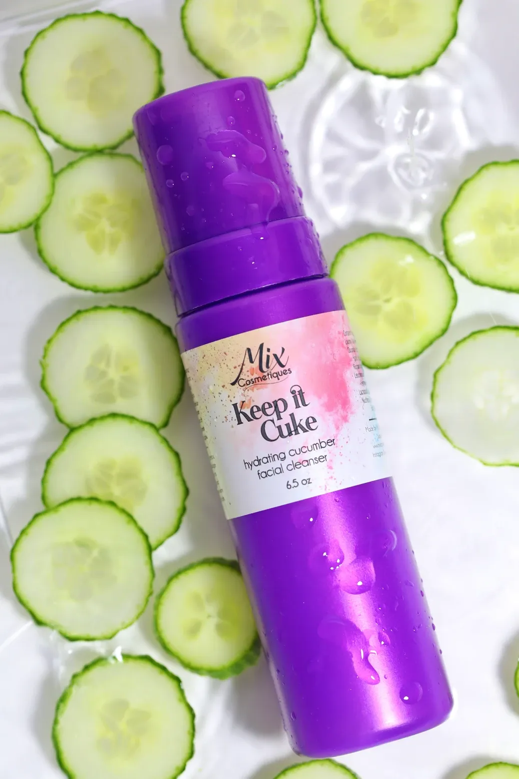 Purple deodorant containers displayed on a background of fresh sliced cucumber circles arranged in a pattern.