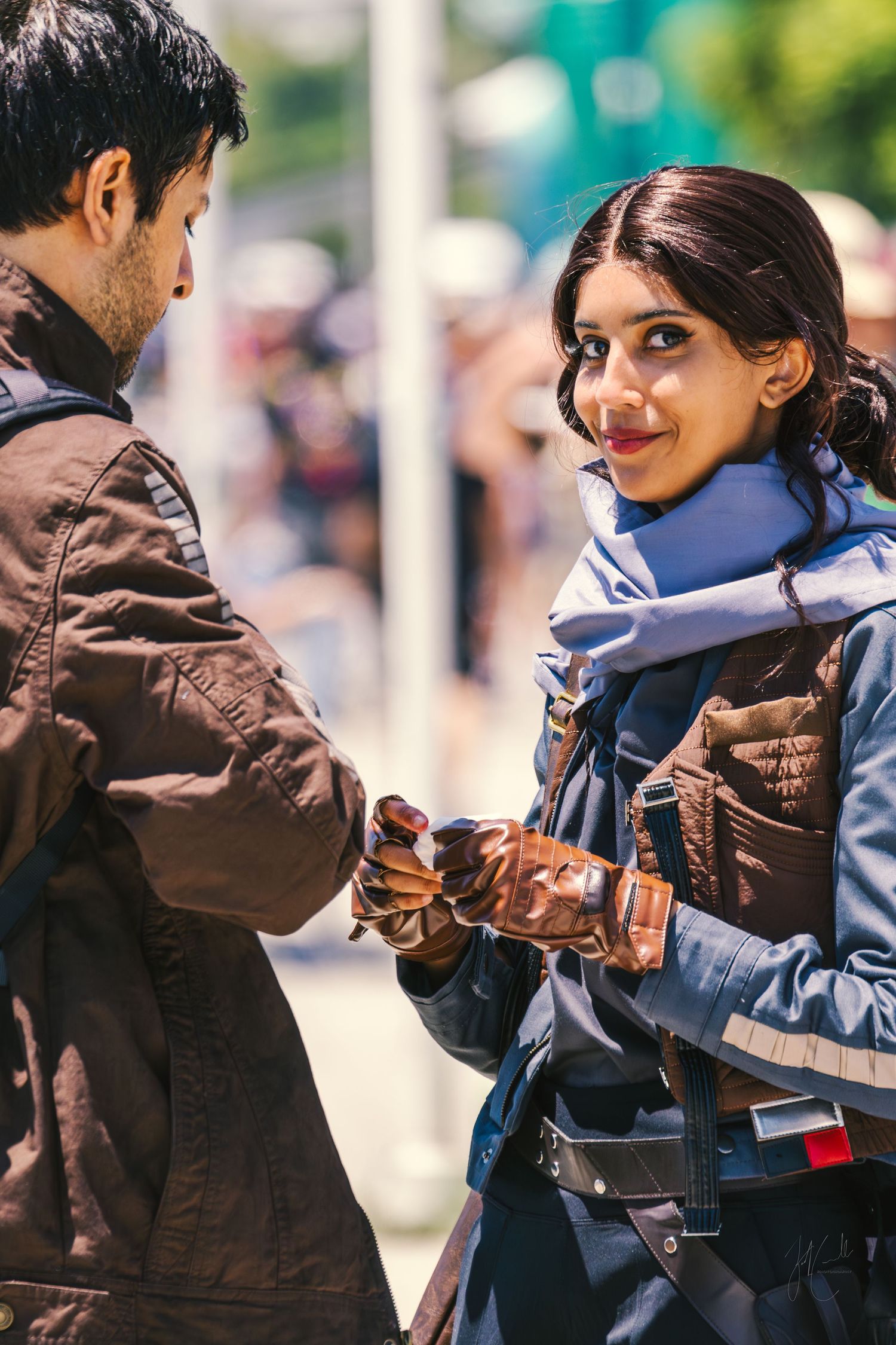 People walking outdoors wearing casual jackets on a sunny day.