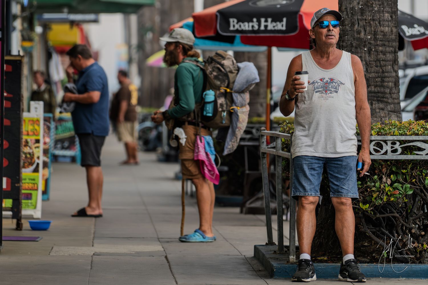 Street vendors and pedestrians gather along a palm tree lined walkway.
