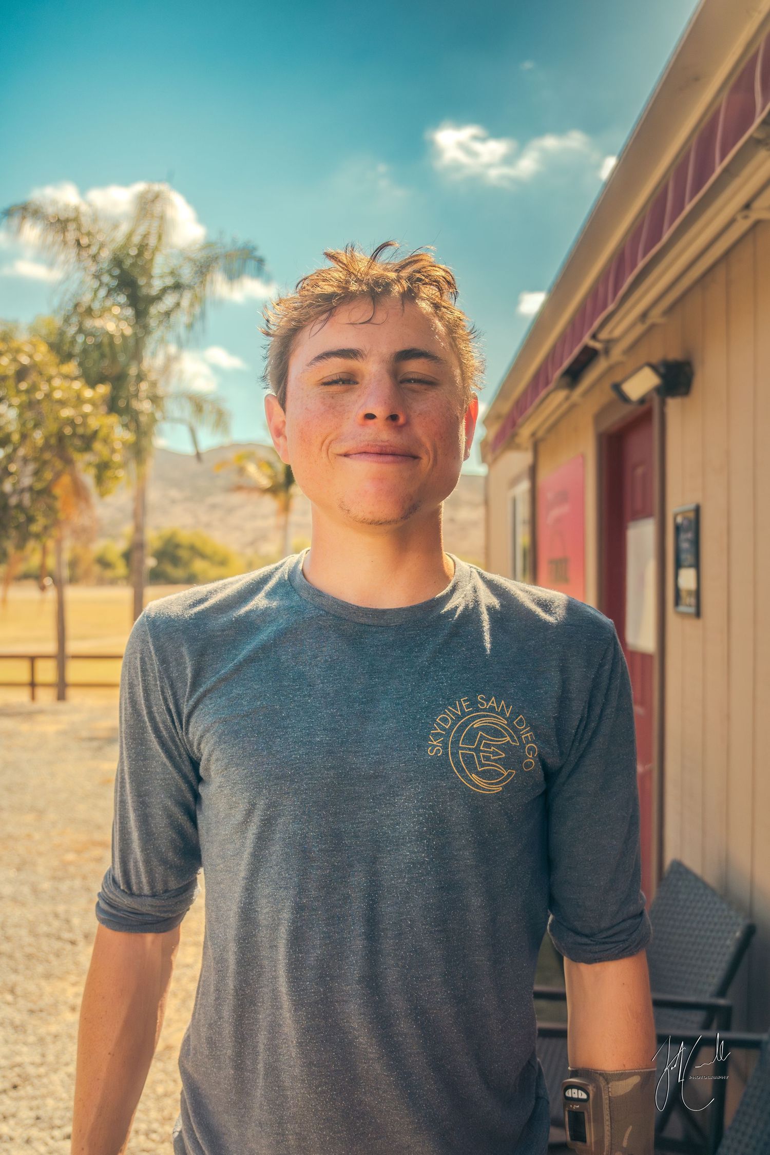 Portrait against desert backdrop shows someone in a grey t-shirt on a sunny day.