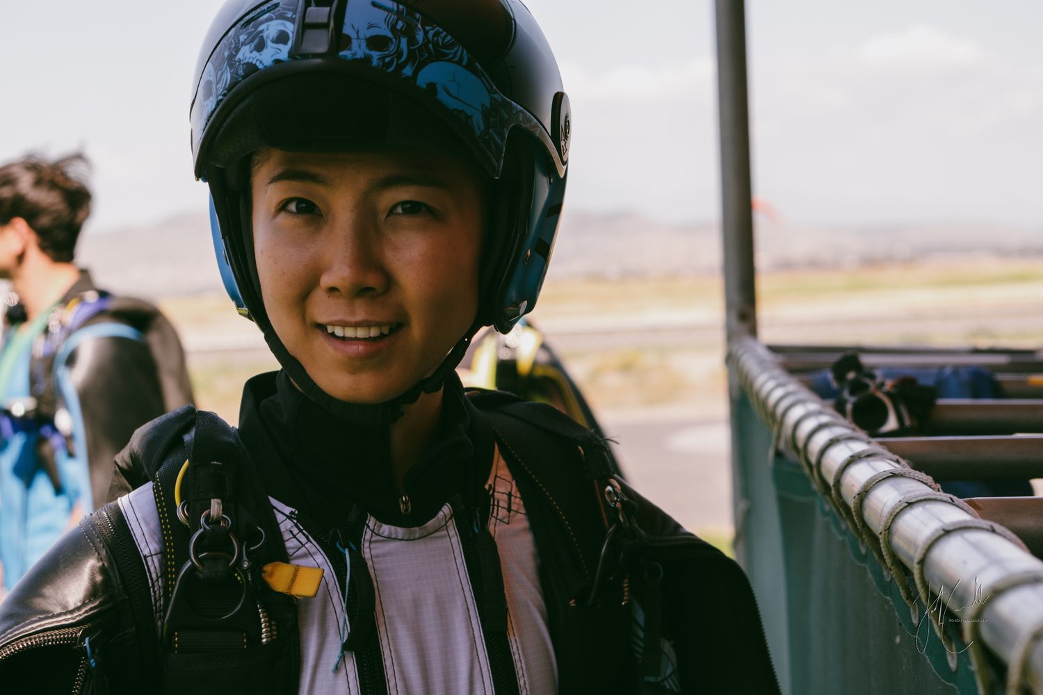 People wearing motorcycle helmets looking through viewfinders at a scenic overlook.