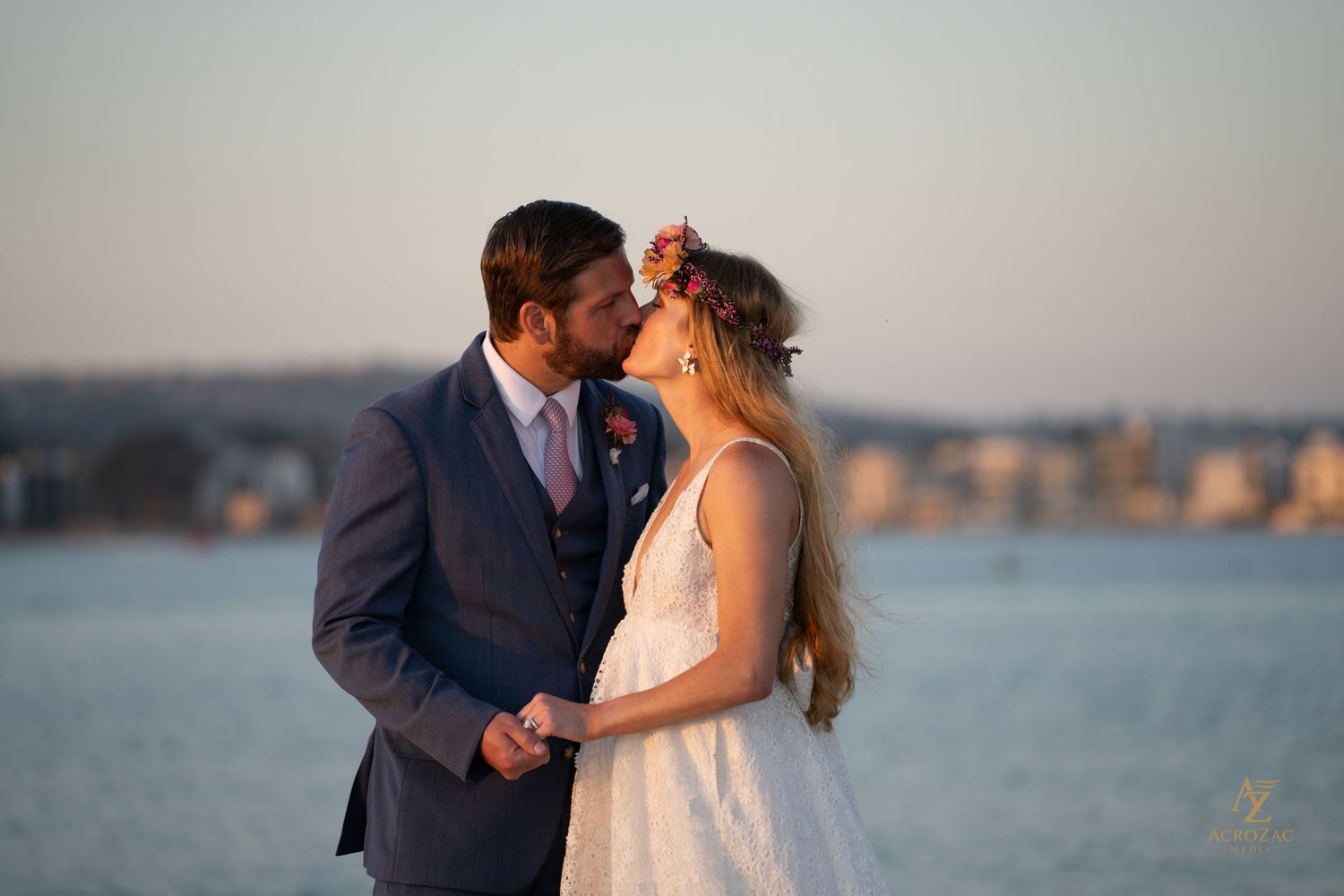 Couple shares romantic sunset moment by the water with city skyline in background.