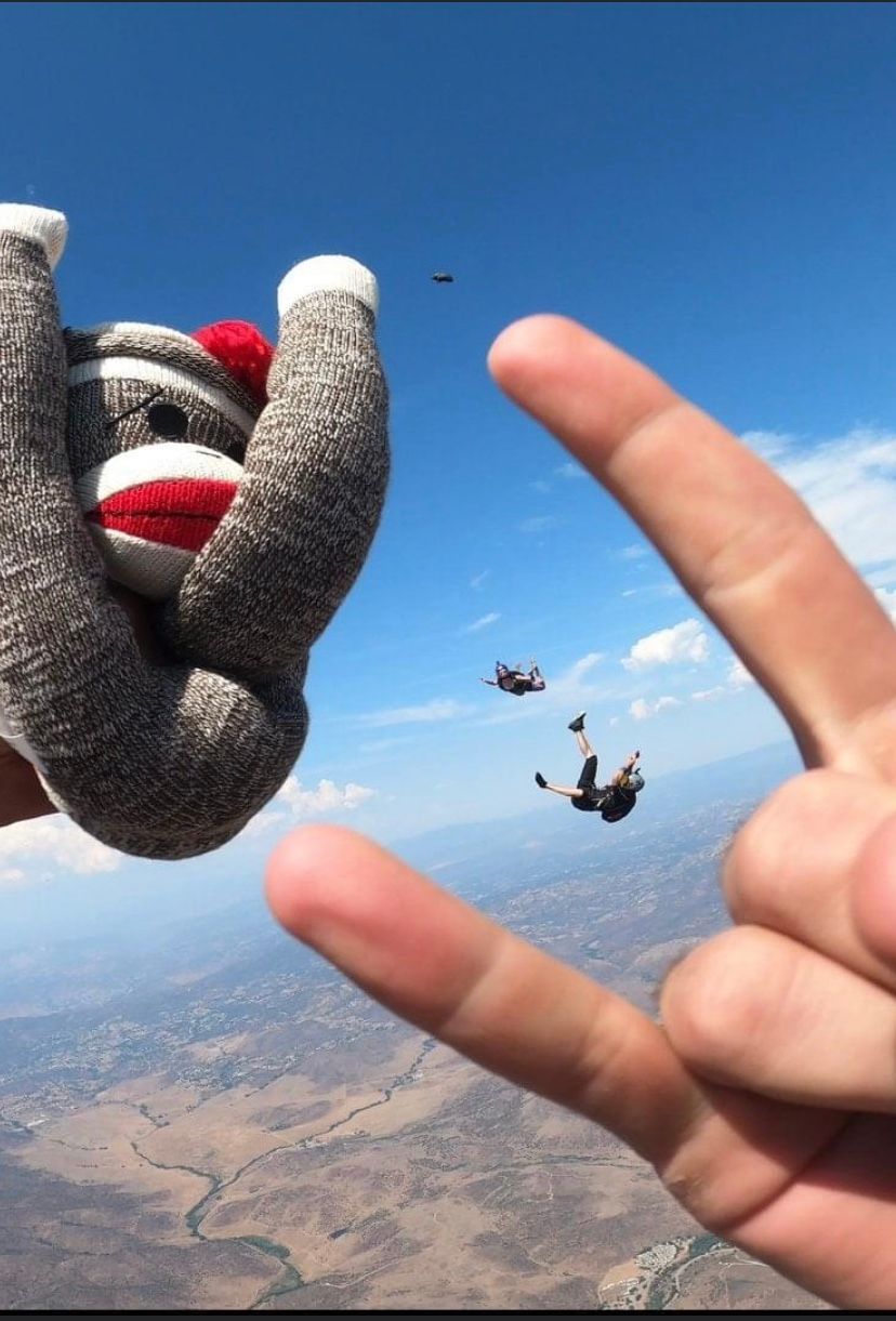 Multiple skydivers performing aerial formations and maneuvers against a clear blue sky.