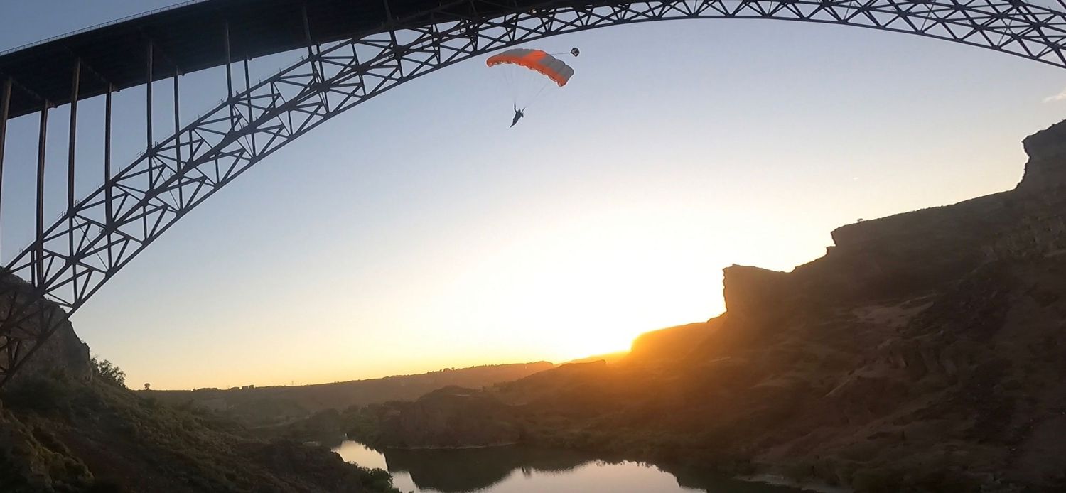 Panoramic silhouette of a bridge structure against a dramatic sunset sky.