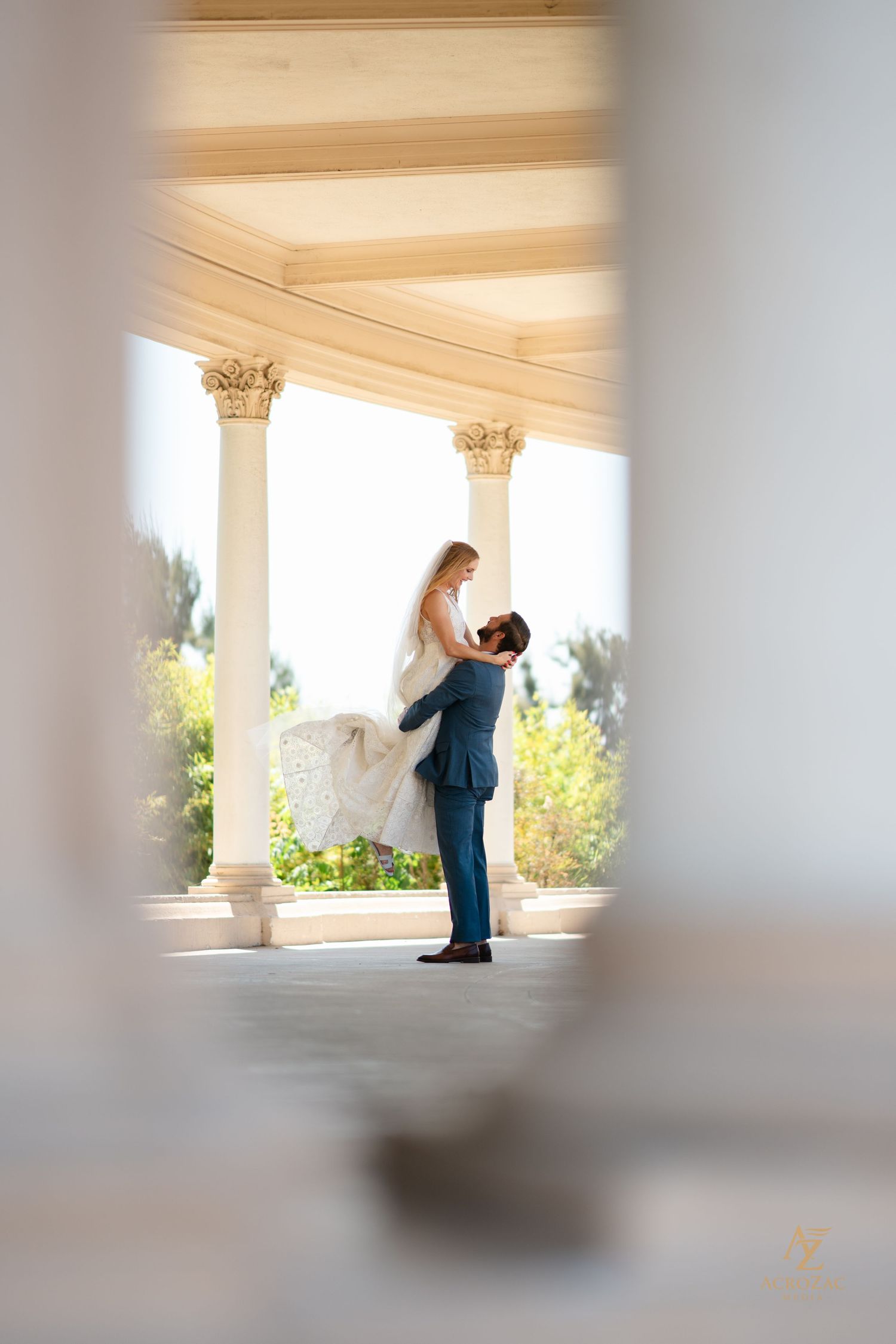 Romantic wedding moment captured through architectural columns with soft focus.