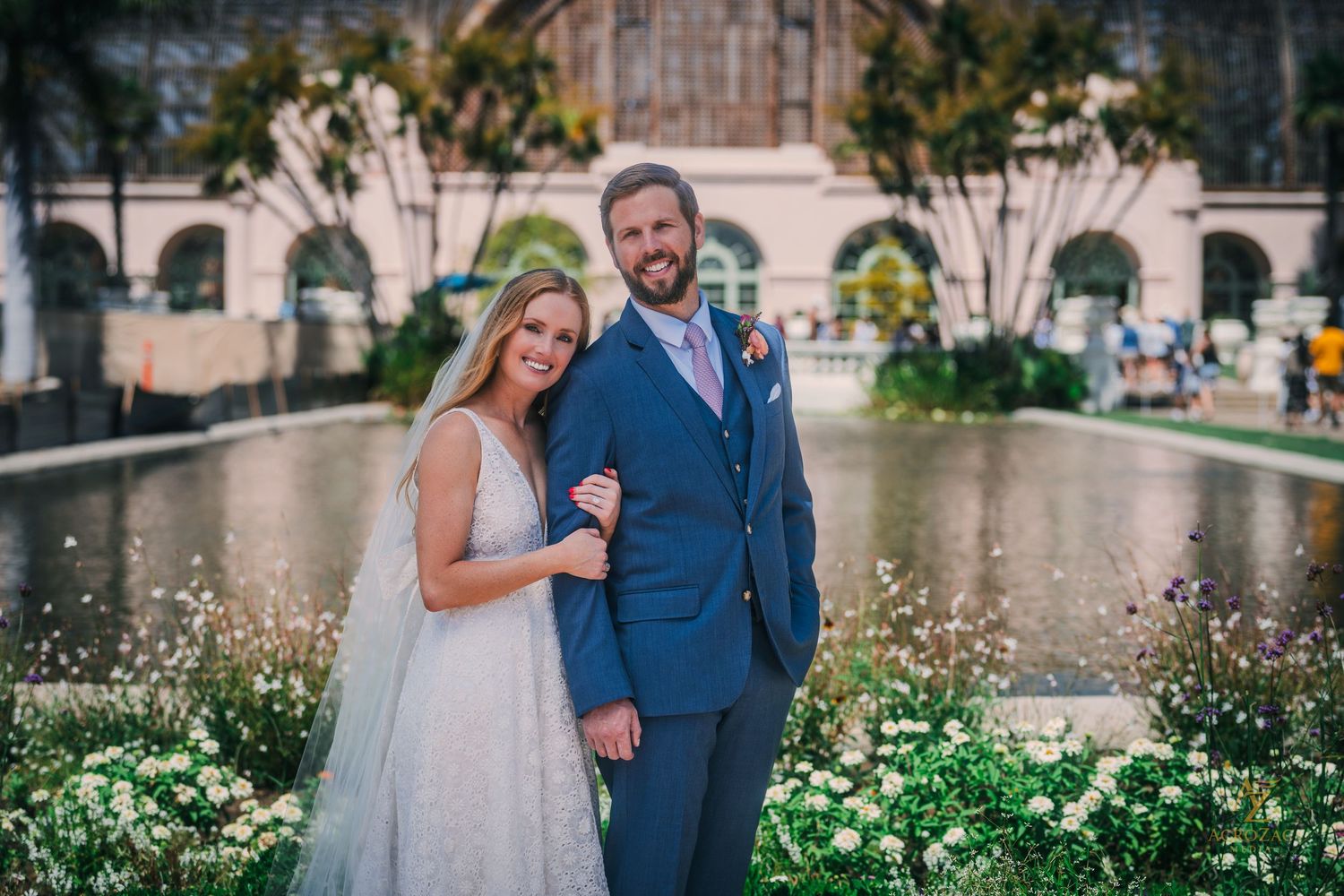 Couple shares a romantic moment in a garden setting with blooming flowers and greenery.