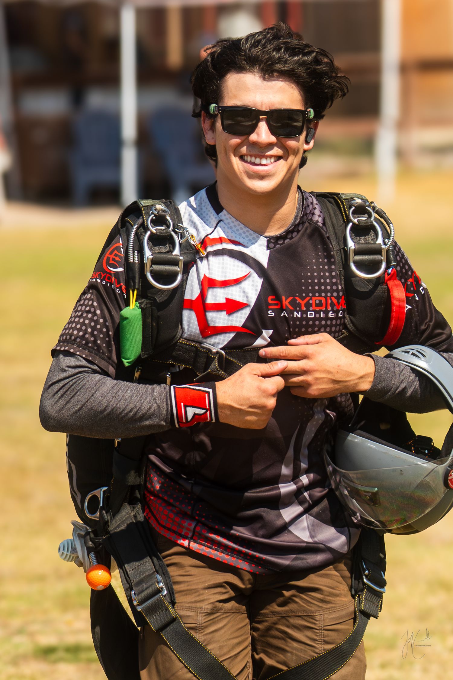 Skydiver in protective gear and sunglasses preparing for jump on sunny day.