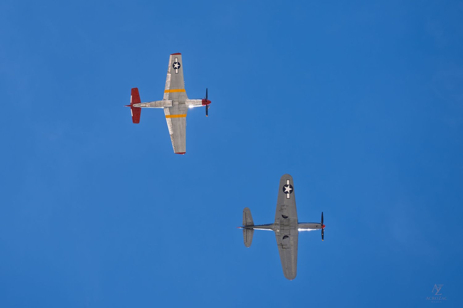 Multiple small aircraft performing aerial maneuvers against bright blue sky.