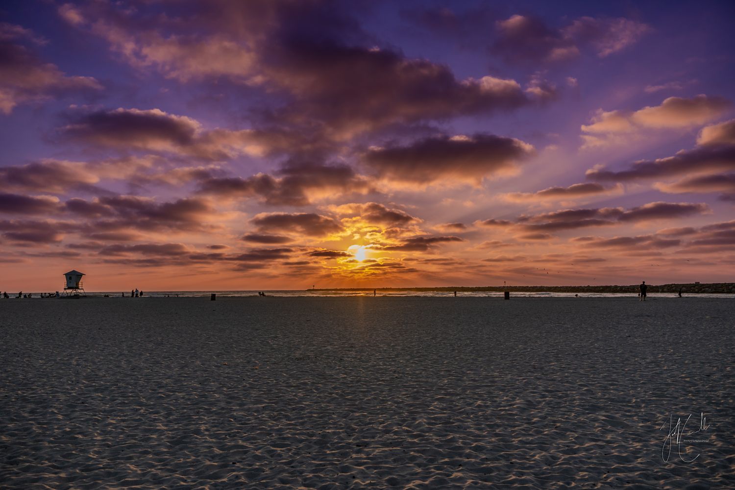 Panoramic sunset over a dark landscape with dramatic purple and orange clouds.
