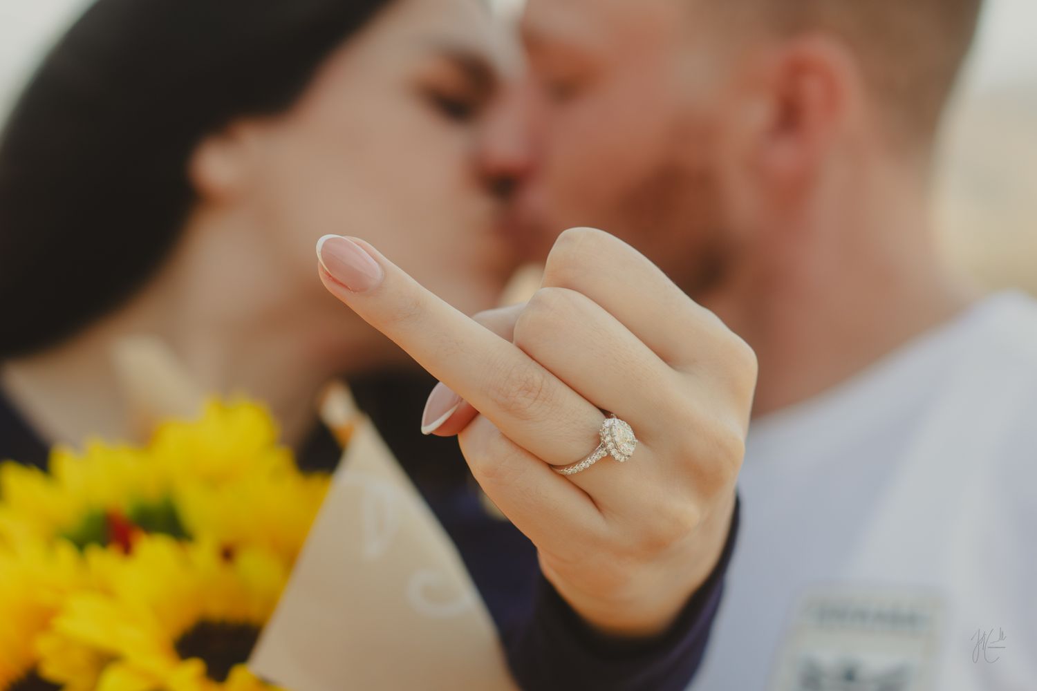 Close-up of hands showing an engagement ring against a blurred background.