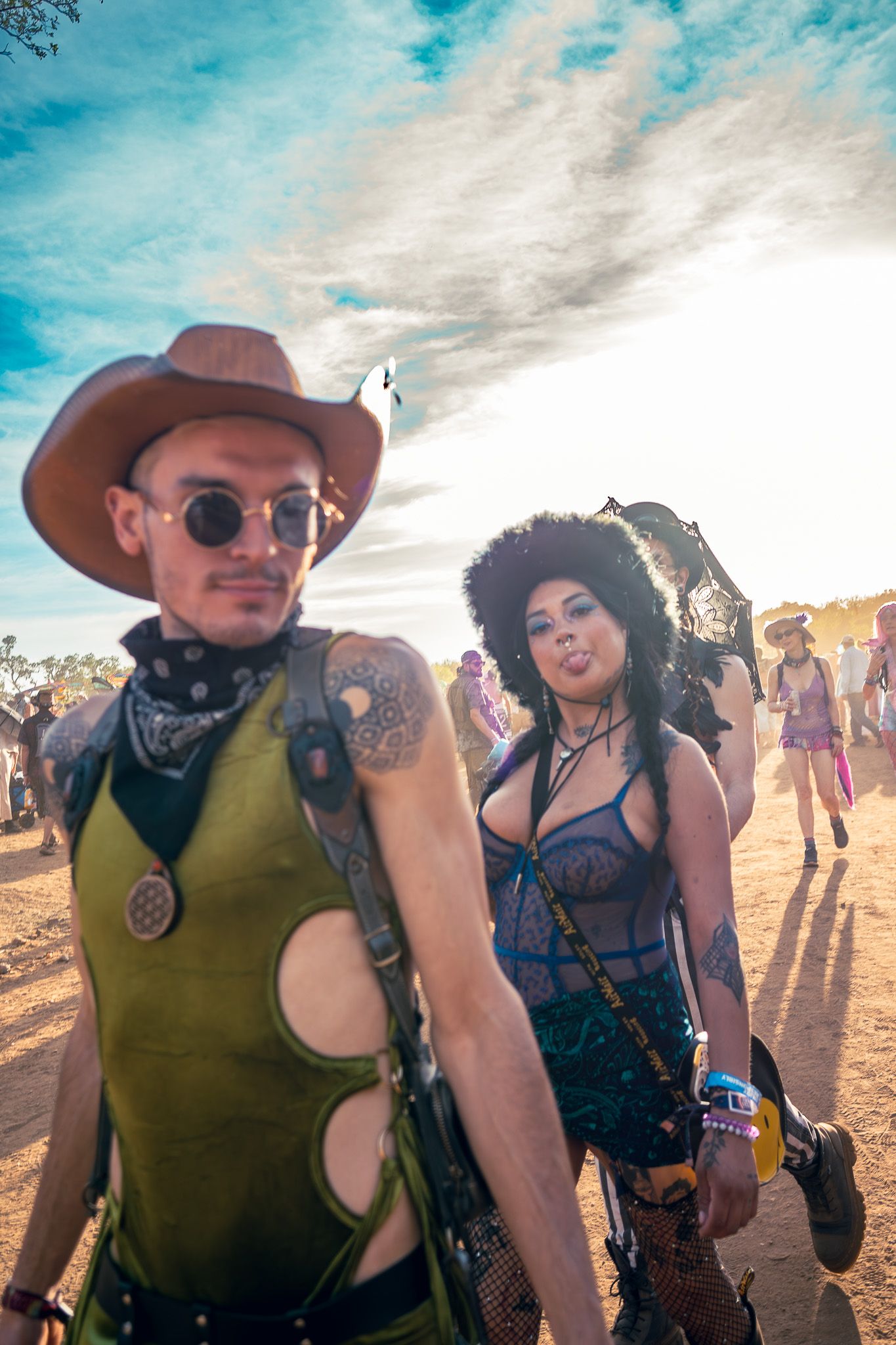 Festival goers in western-inspired outfits pose together under bright desert sky.