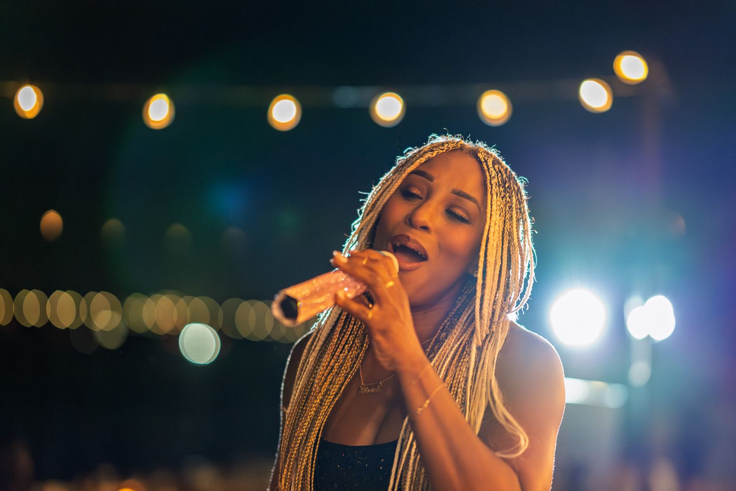 Concert stage illuminated with string lights and spotlights creating a warm atmospheric glow.