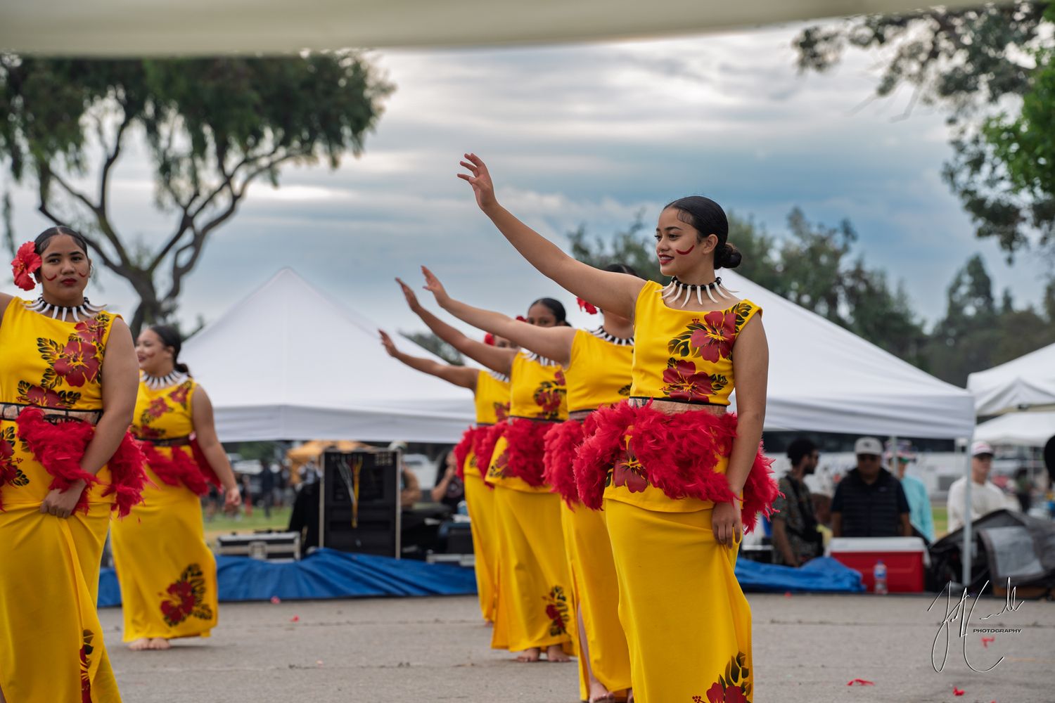 Dancers in bright yellow traditional costumes performing at an outdoor festival.