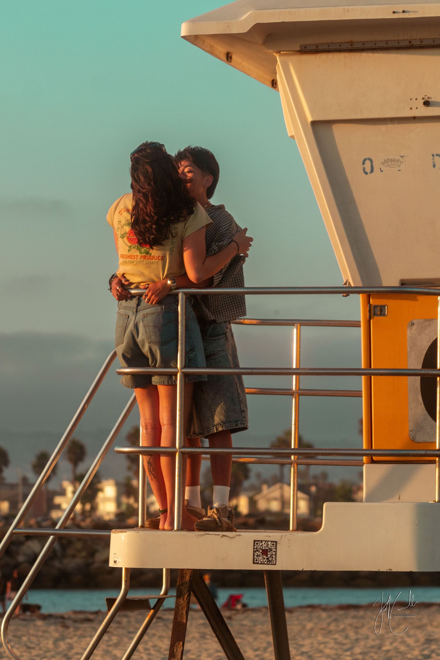 Couple standing on beach observation deck during golden hour.