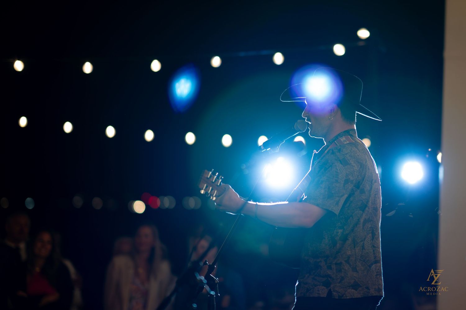 Concert stage with string lights and blue spotlights creating atmospheric ambiance.