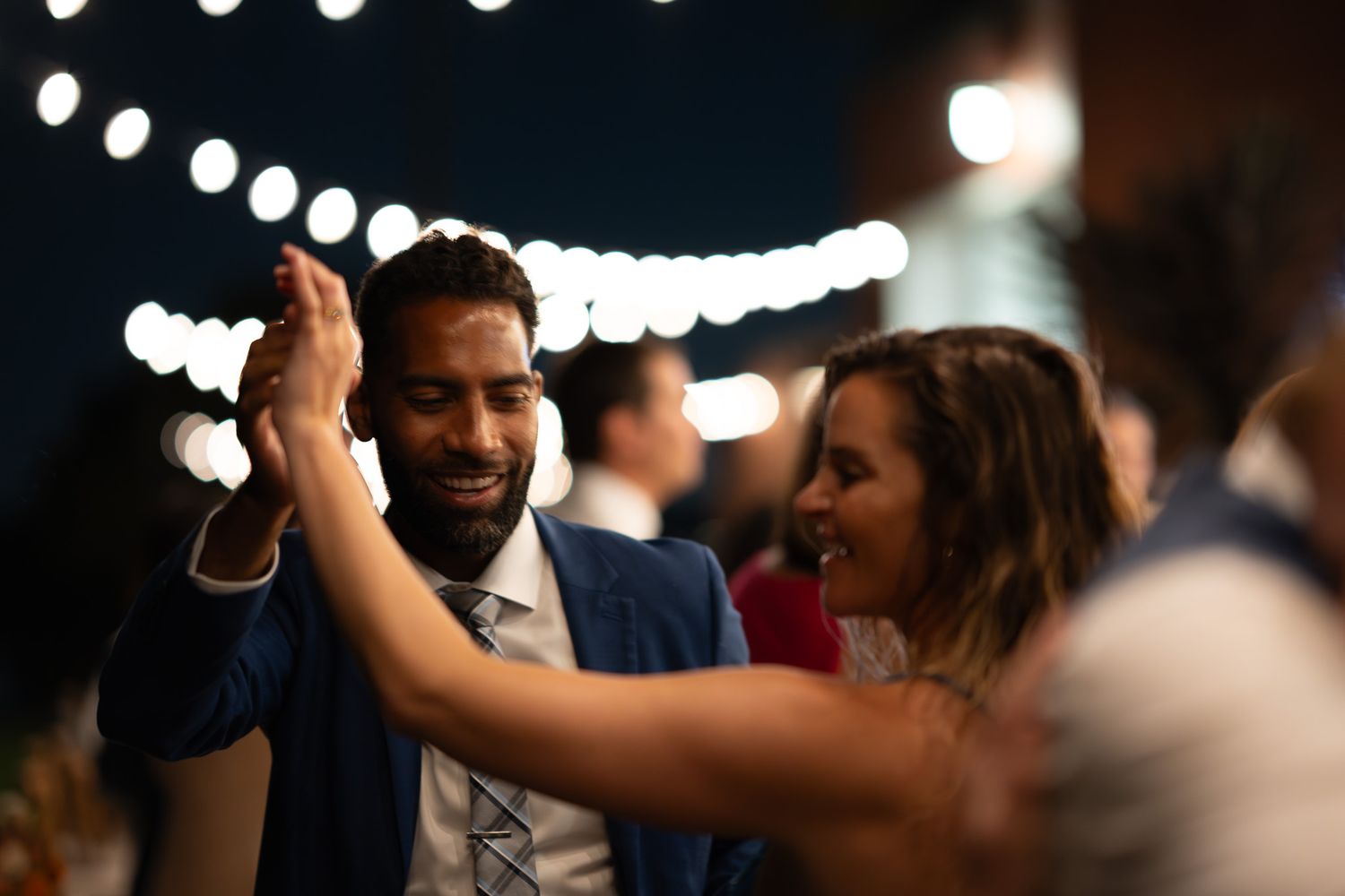 String lights create a bokeh effect at an evening outdoor celebration.