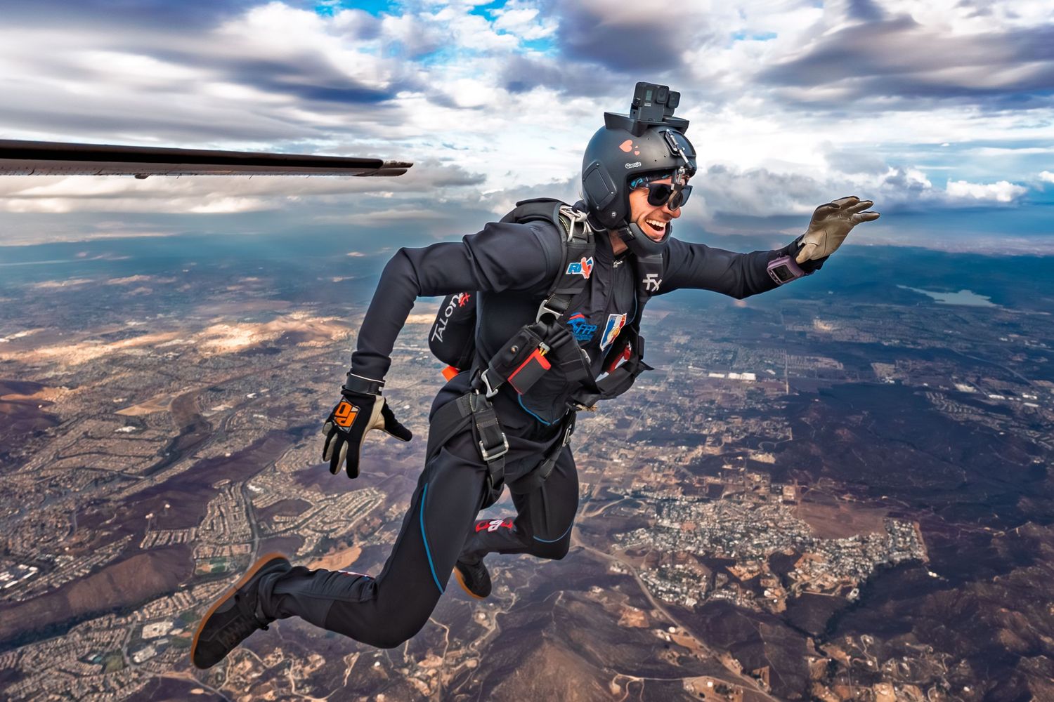 Skydivers soaring through clouds over mountainous landscape during a group formation jump.