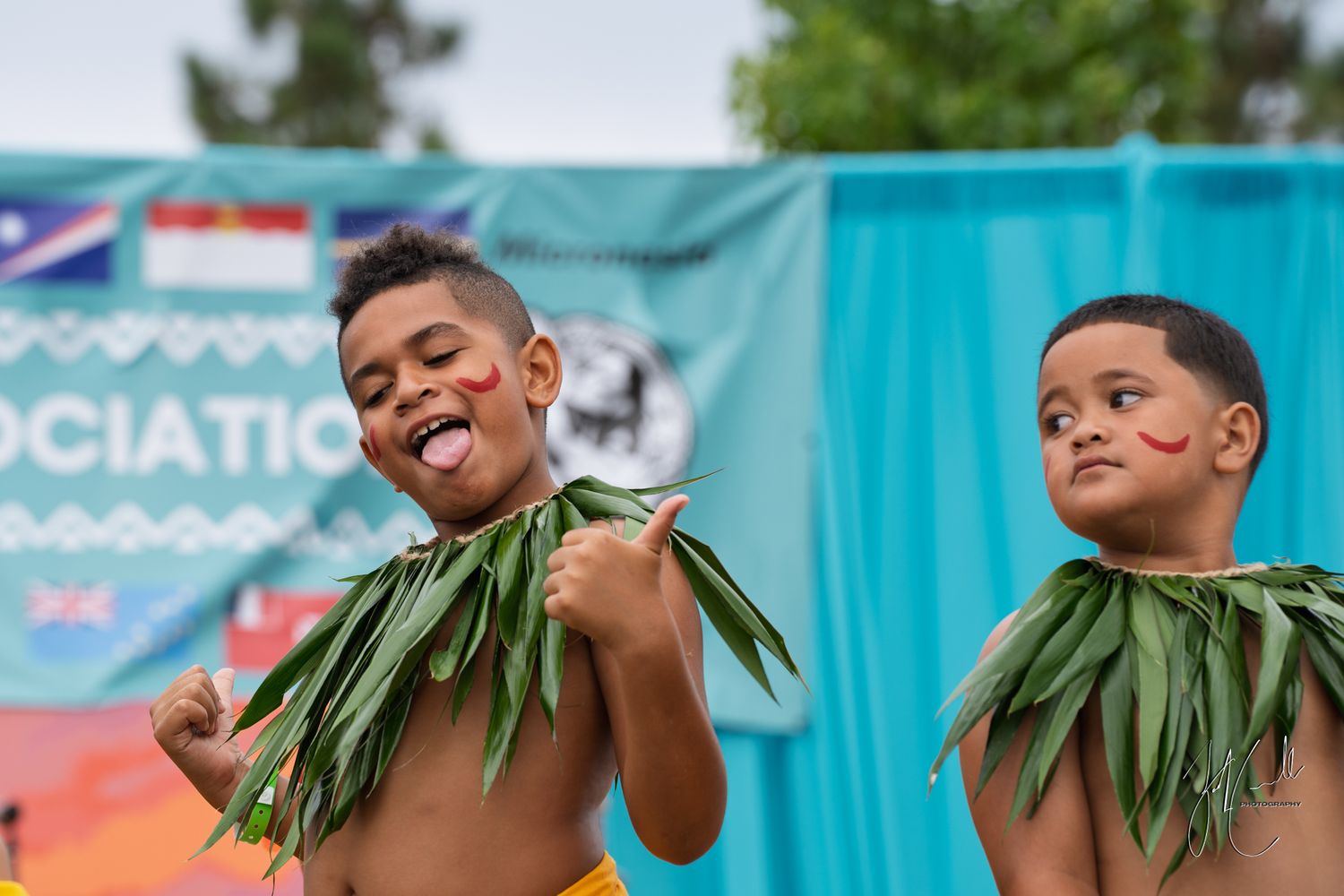 Traditional Hawaiian dancers performing with palm fronds against a bright blue backdrop.