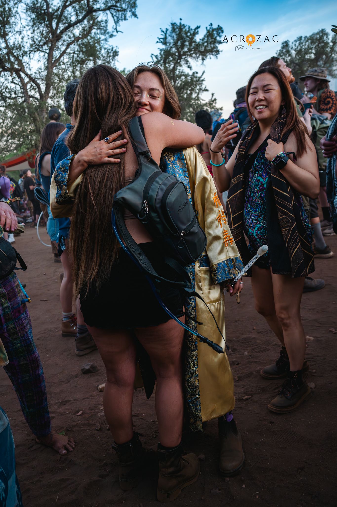 Festival attendees dancing and socializing at an outdoor event during sunset.