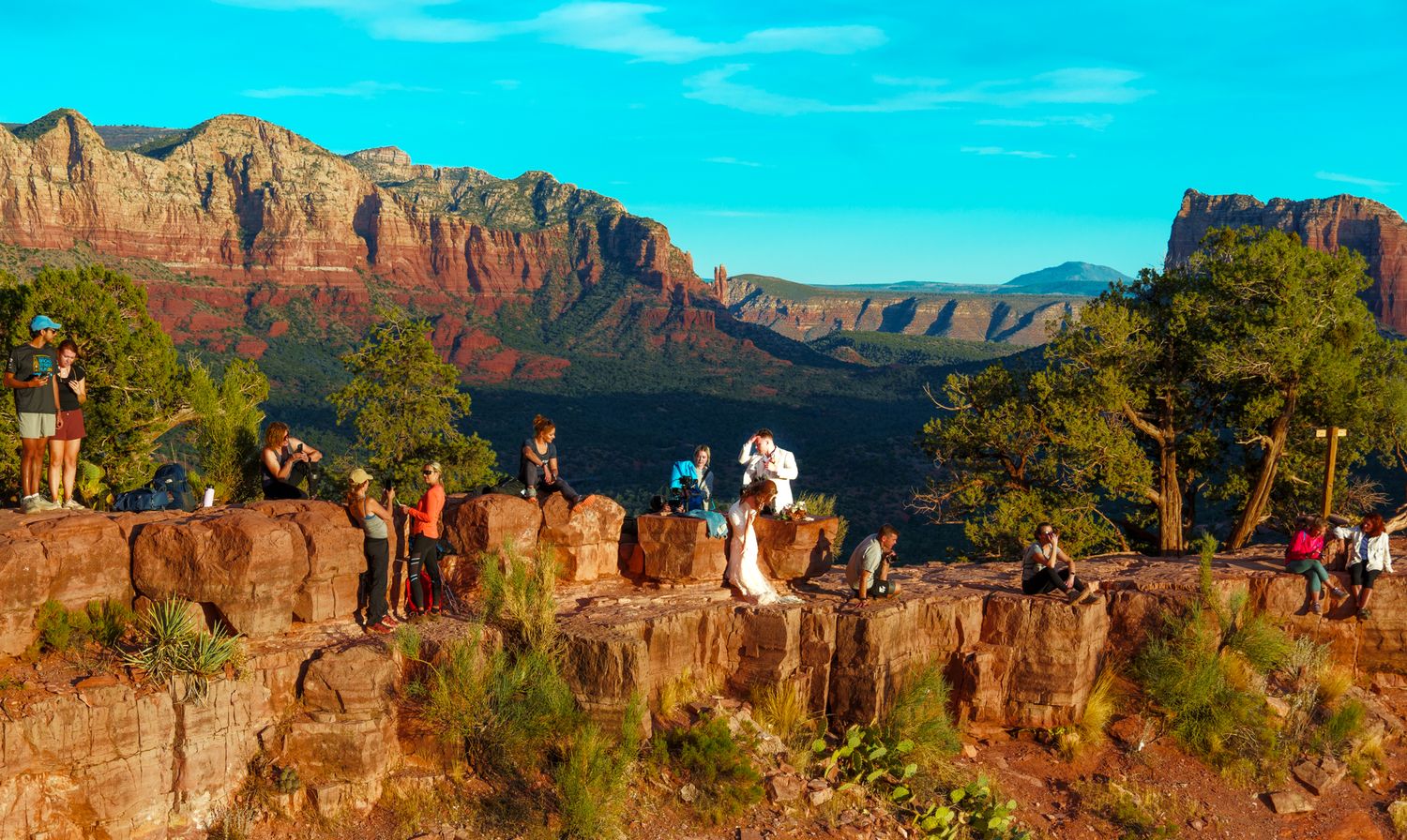 Tourists gathered at scenic overlook viewing red rock formations in Sedona.