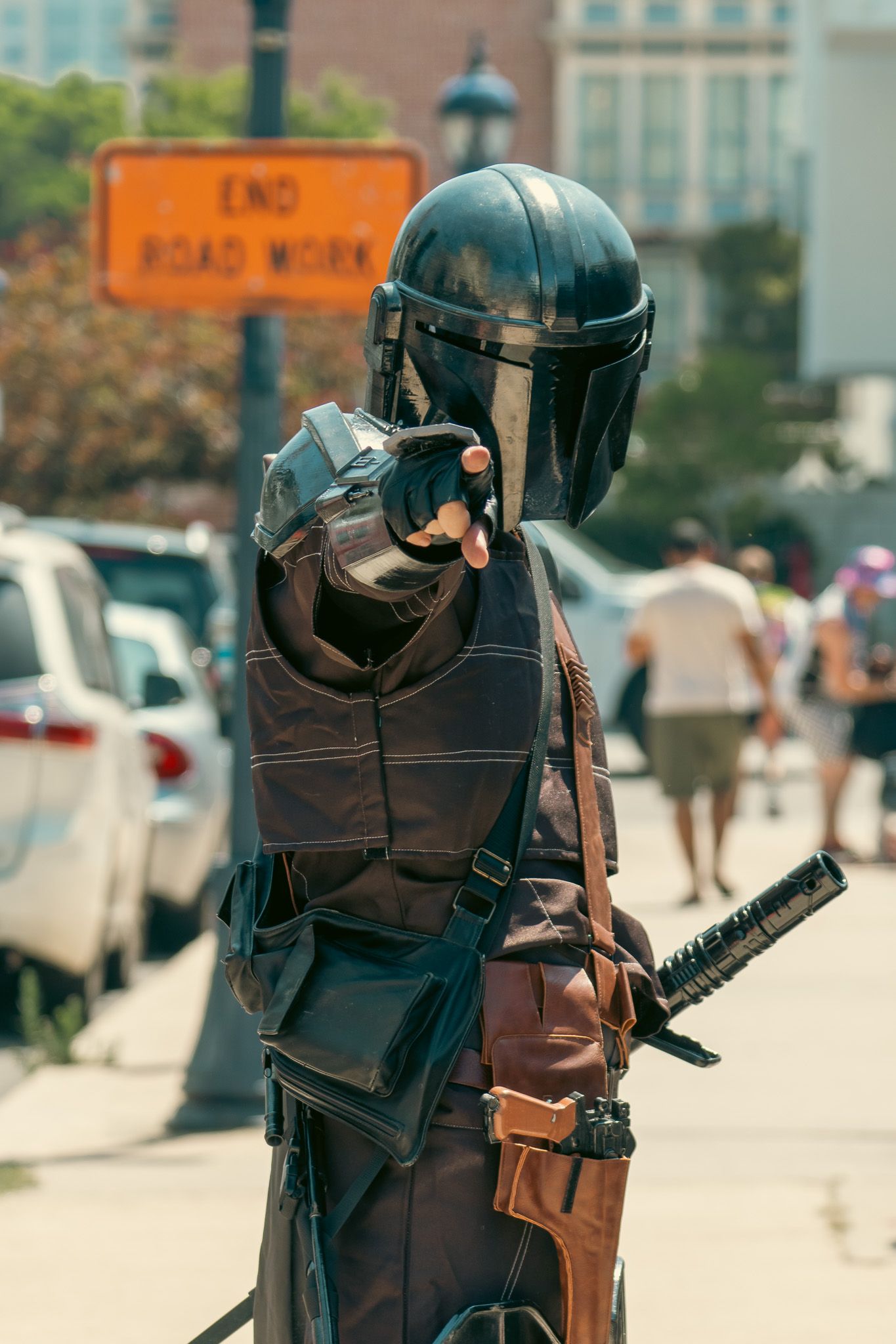 Cosplayer wearing detailed black samurai armor and helmet with sword accessories at an outdoor event.
