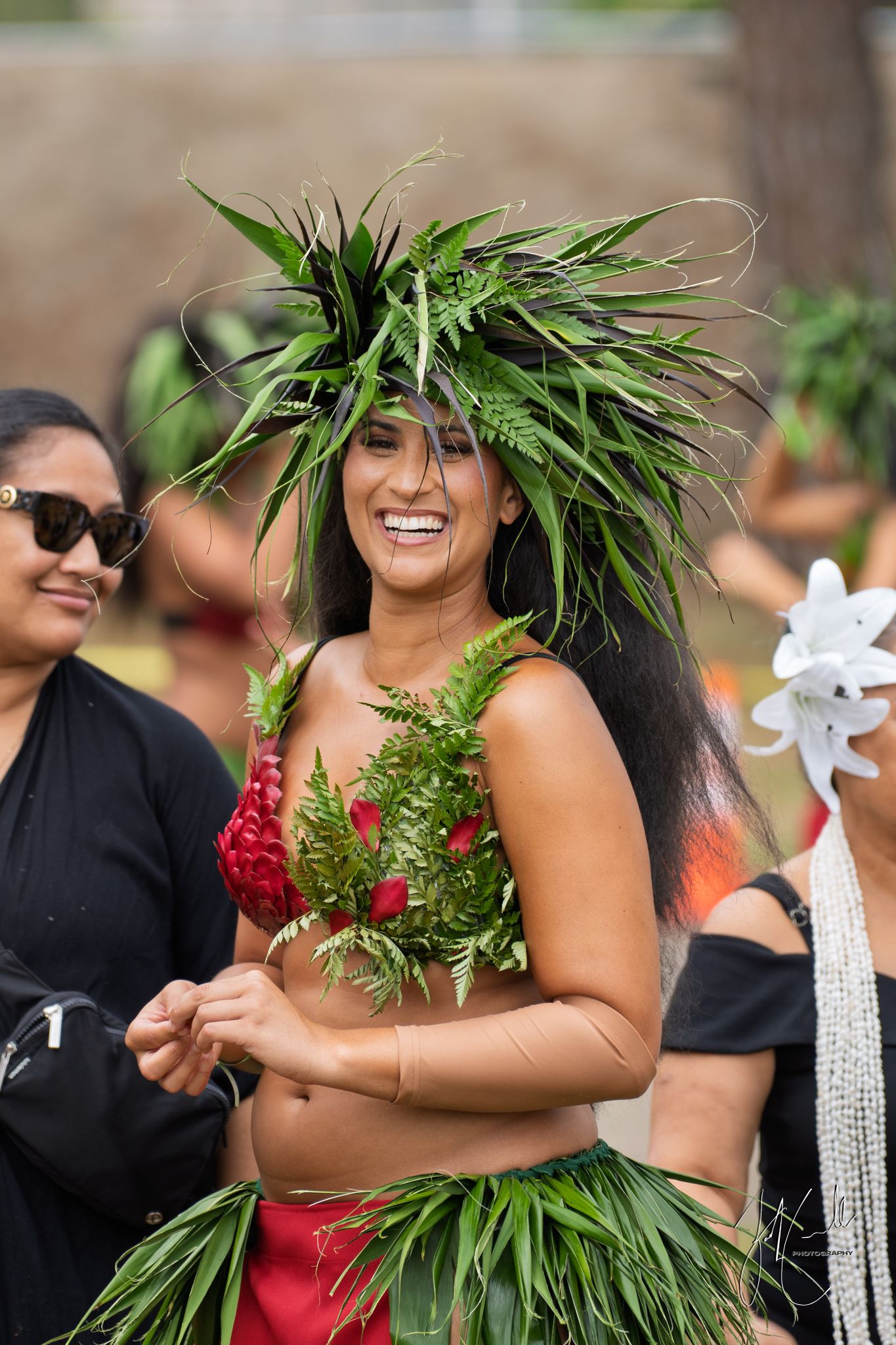 Traditional Hawaiian hula dancers performing in tropical setting with lei and grass skirts.