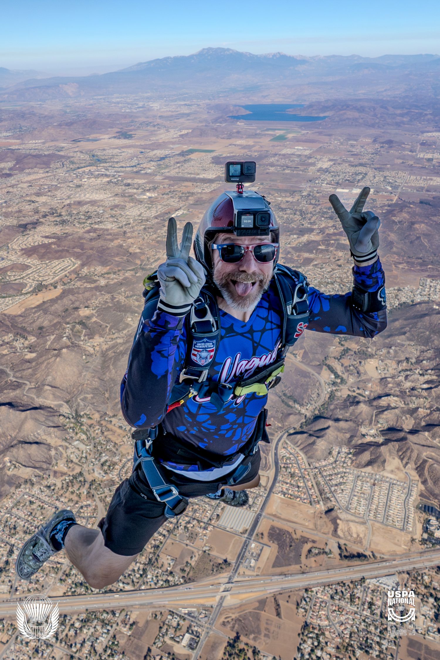 Aerial photographer capturing footage while skydiving over mountainous terrain.