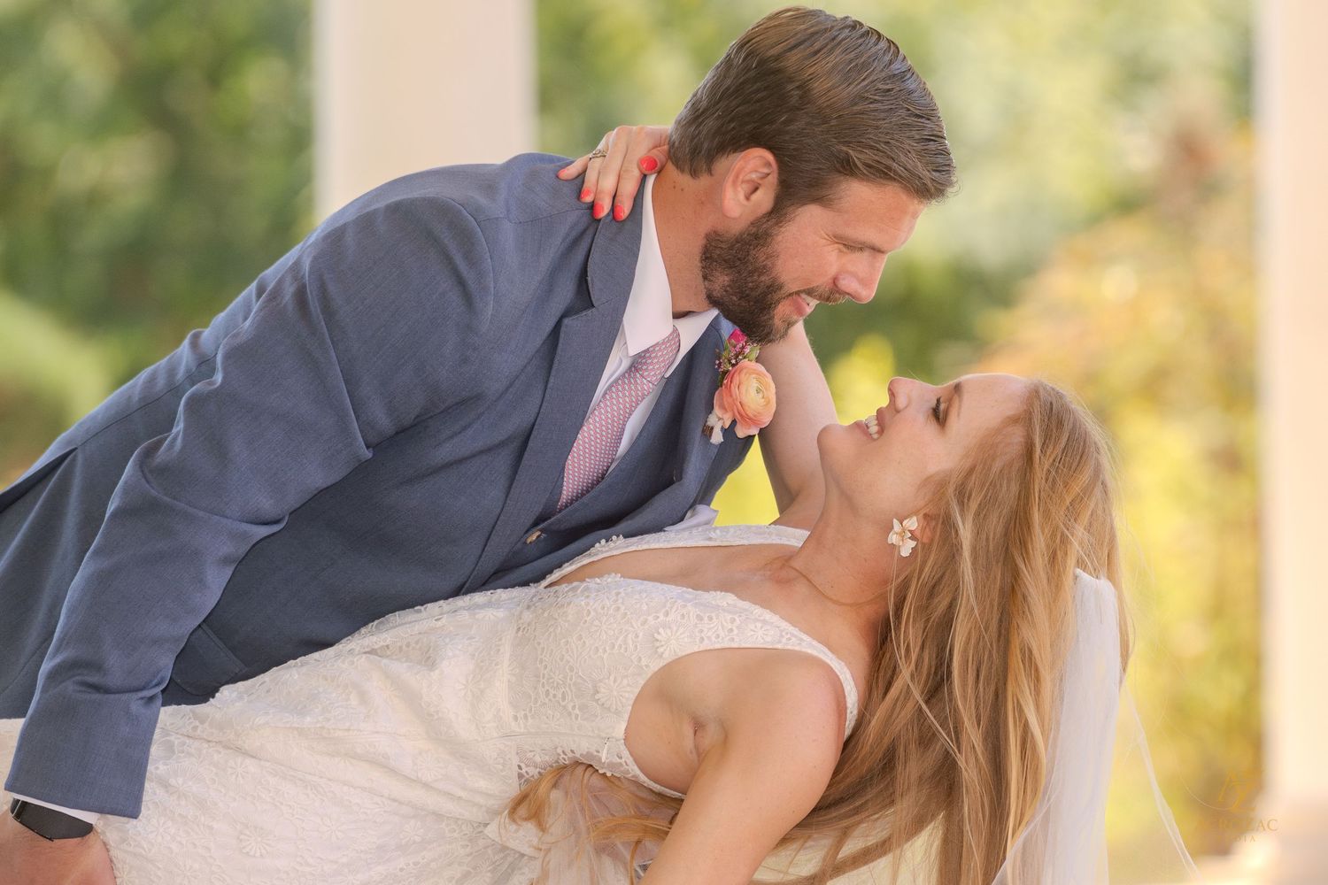 Newlyweds embrace in an outdoor garden setting during golden hour.
