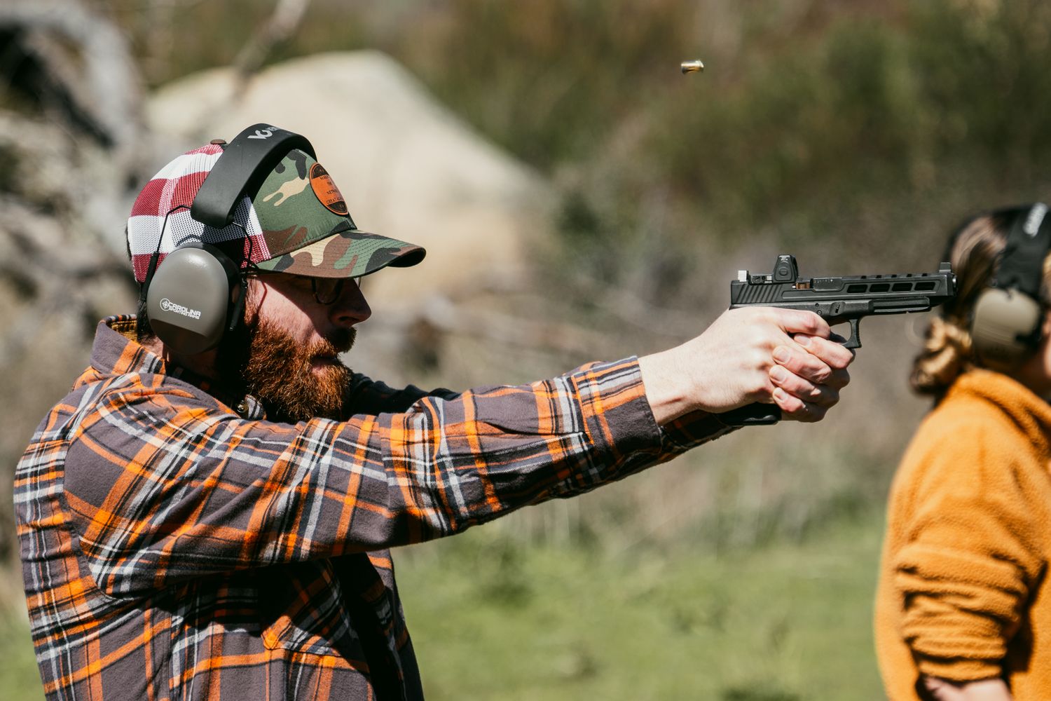 Person practicing target shooting with handgun at outdoor range.