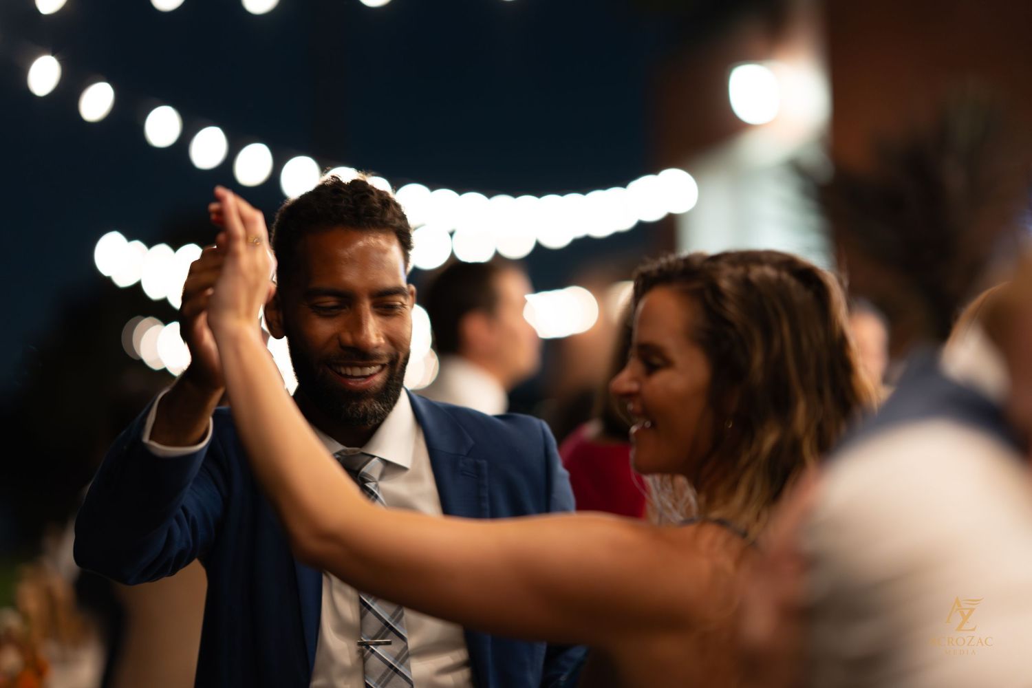 Wedding reception dance party with string lights creating festive atmosphere.