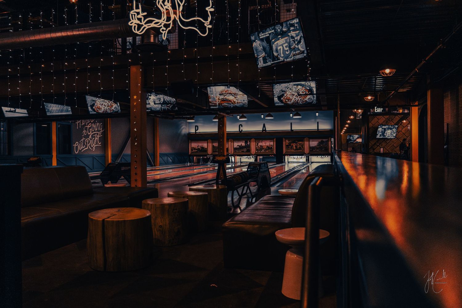 Dark restaurant interior with wooden bar counter and hanging chandelier.