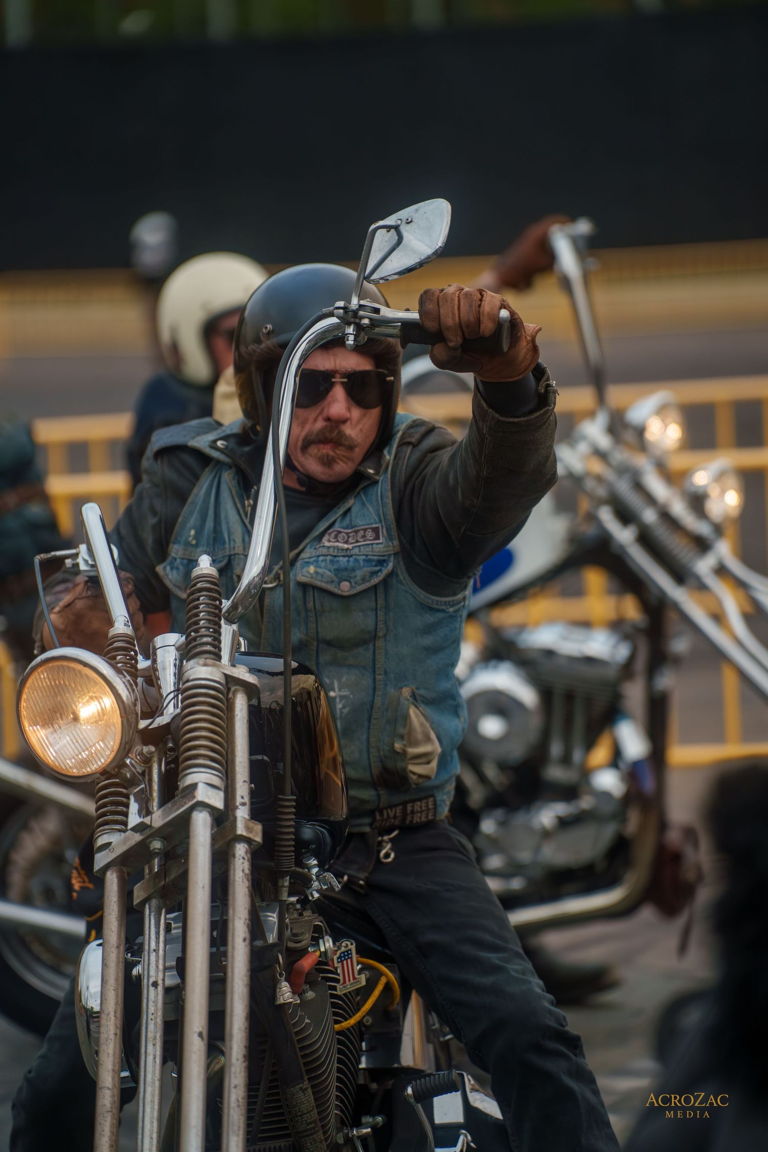 Motorcyclist in winter gear rides a custom chopper motorcycle with tall handlebars at dusk.