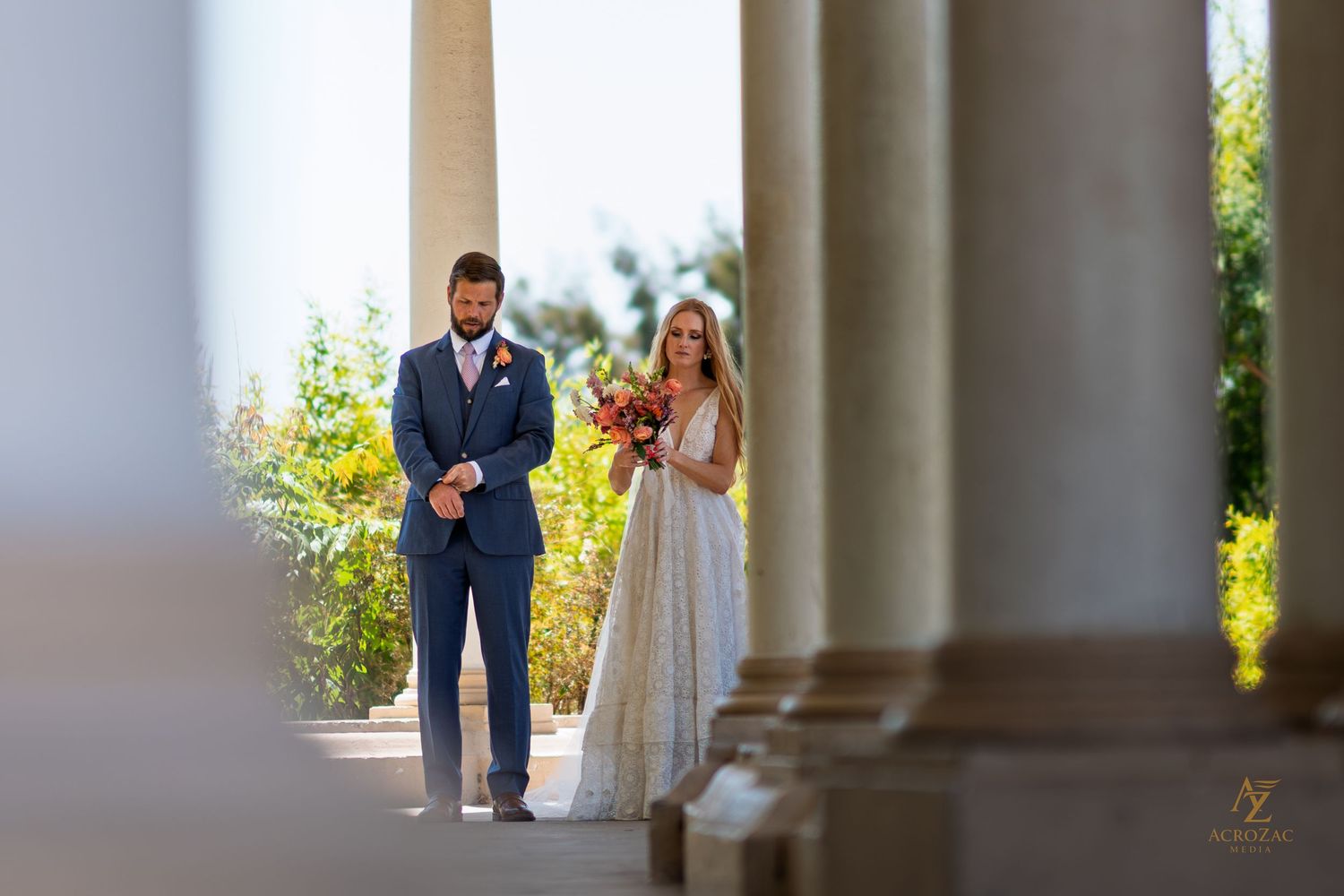 Wedding photography through classical columns creating architectural framing.