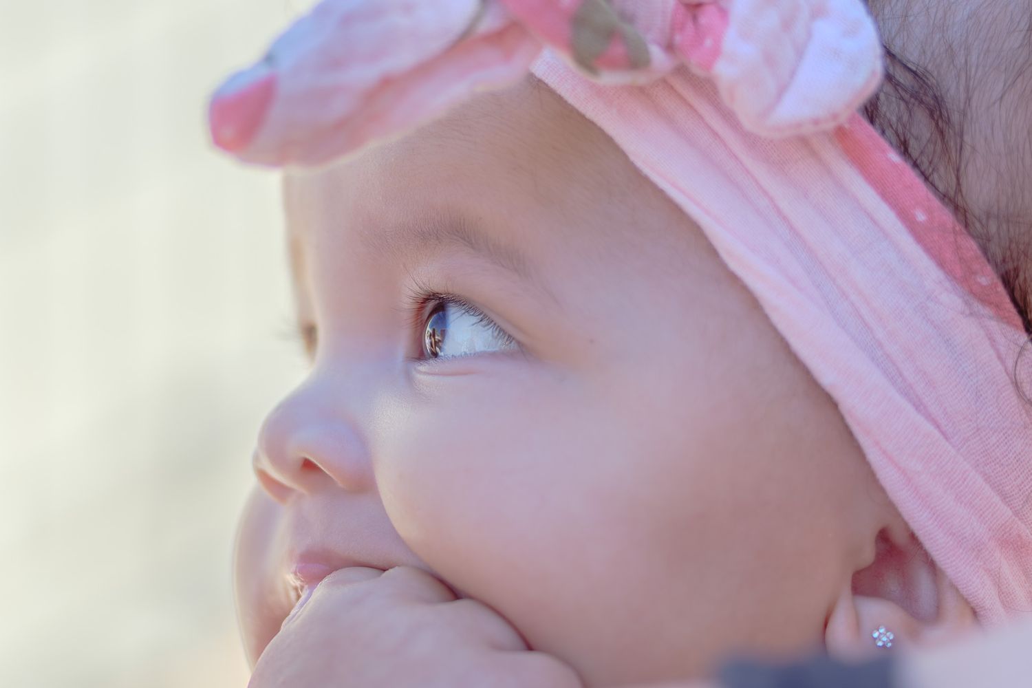 Close-up view of baby wearing pink hat in soft natural lighting.