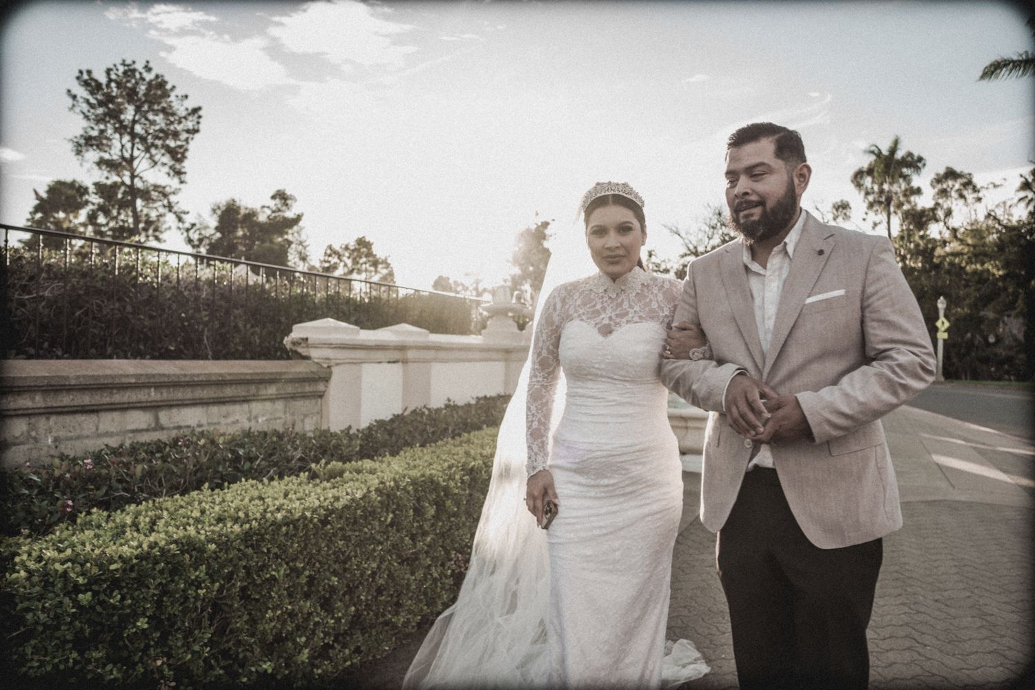 Couple walking along a garden path in formal wedding attire.