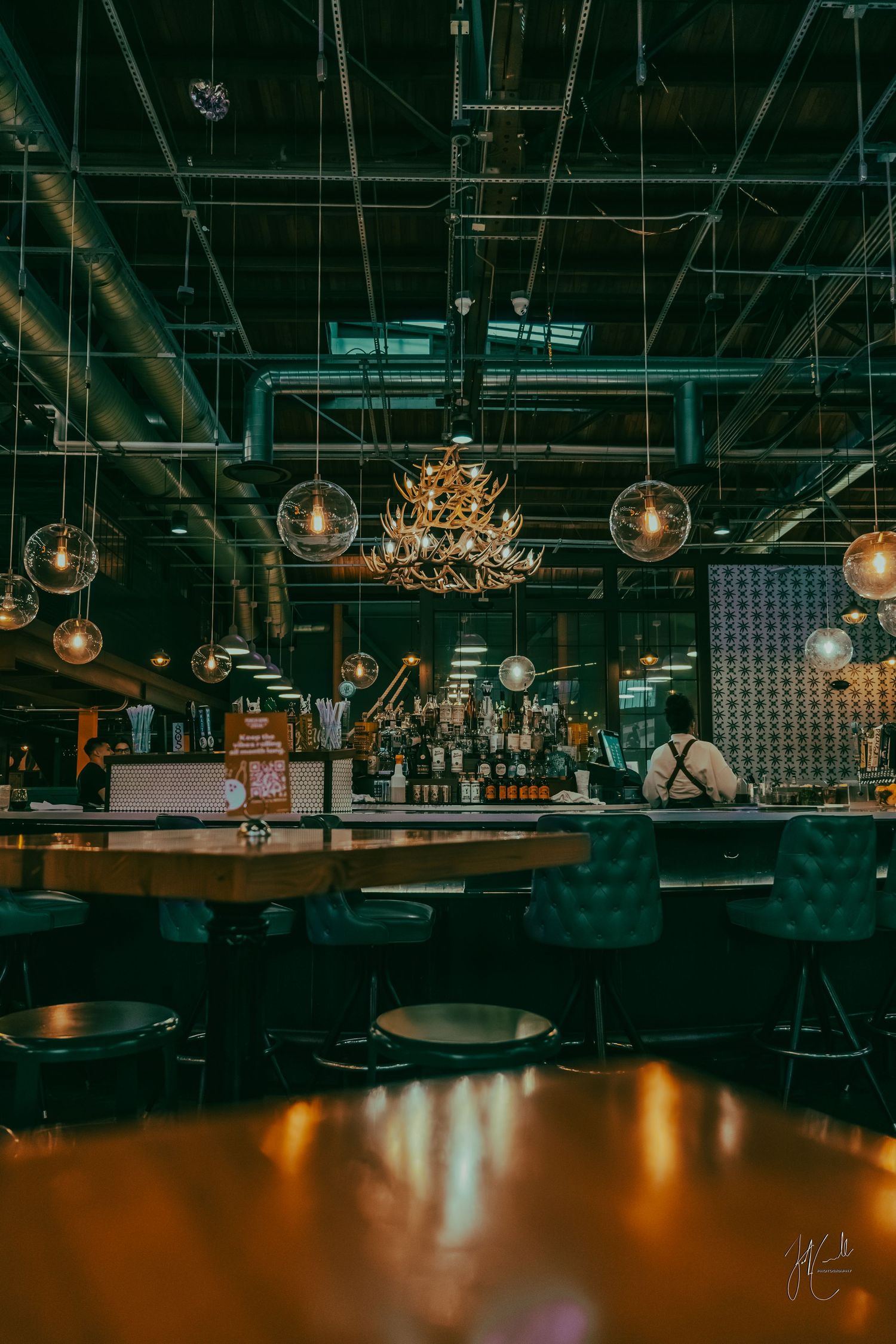 Dark bar interior with hanging pendant lights and industrial decor creating moody ambiance.