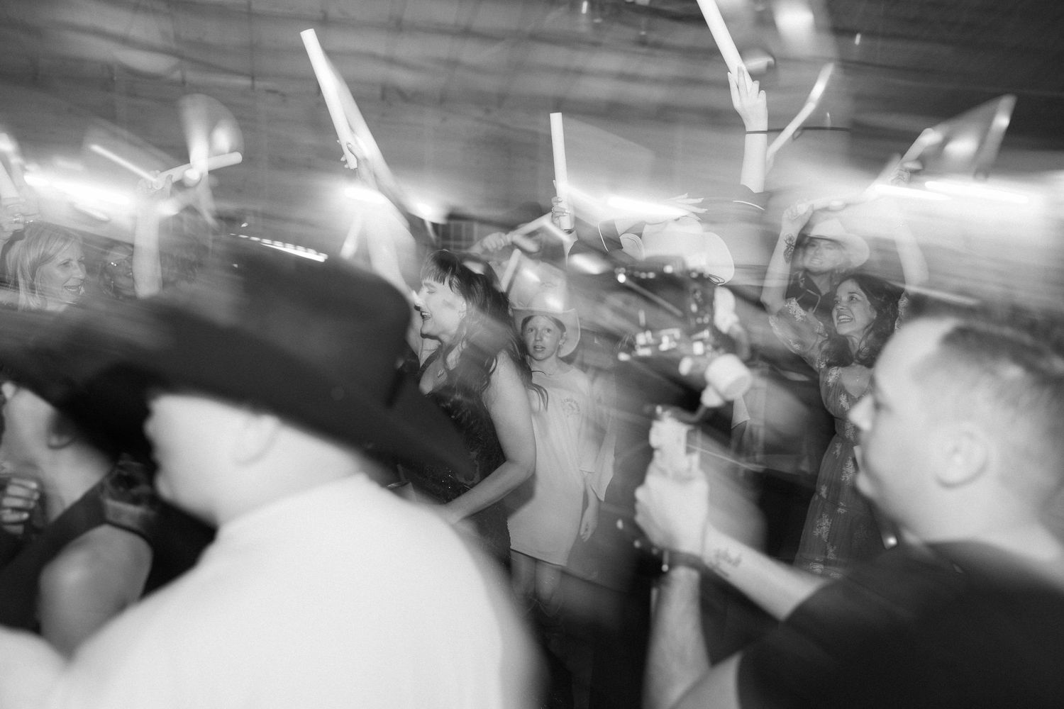 High-energy wedding reception party photo with motion blur, capturing guests dancing. Ideal for a fun, story-driven wedding