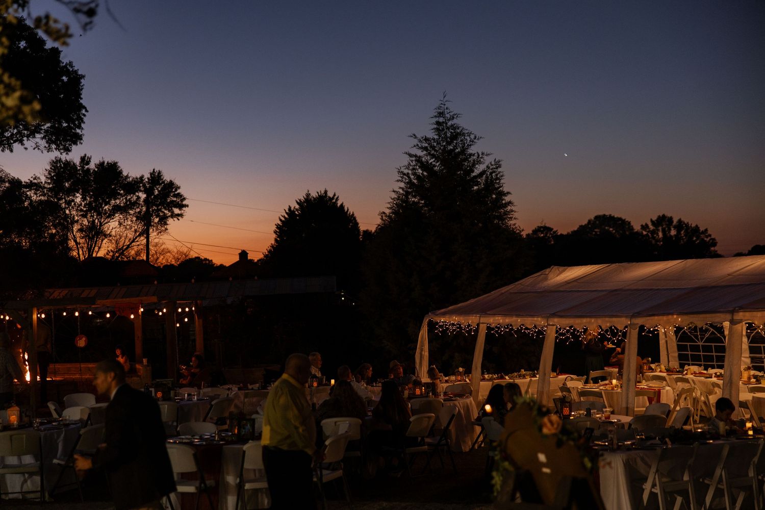 Candid moment during a beautiful luxury tent wedding reception at sunset. Professional videography and photography for high-end events.