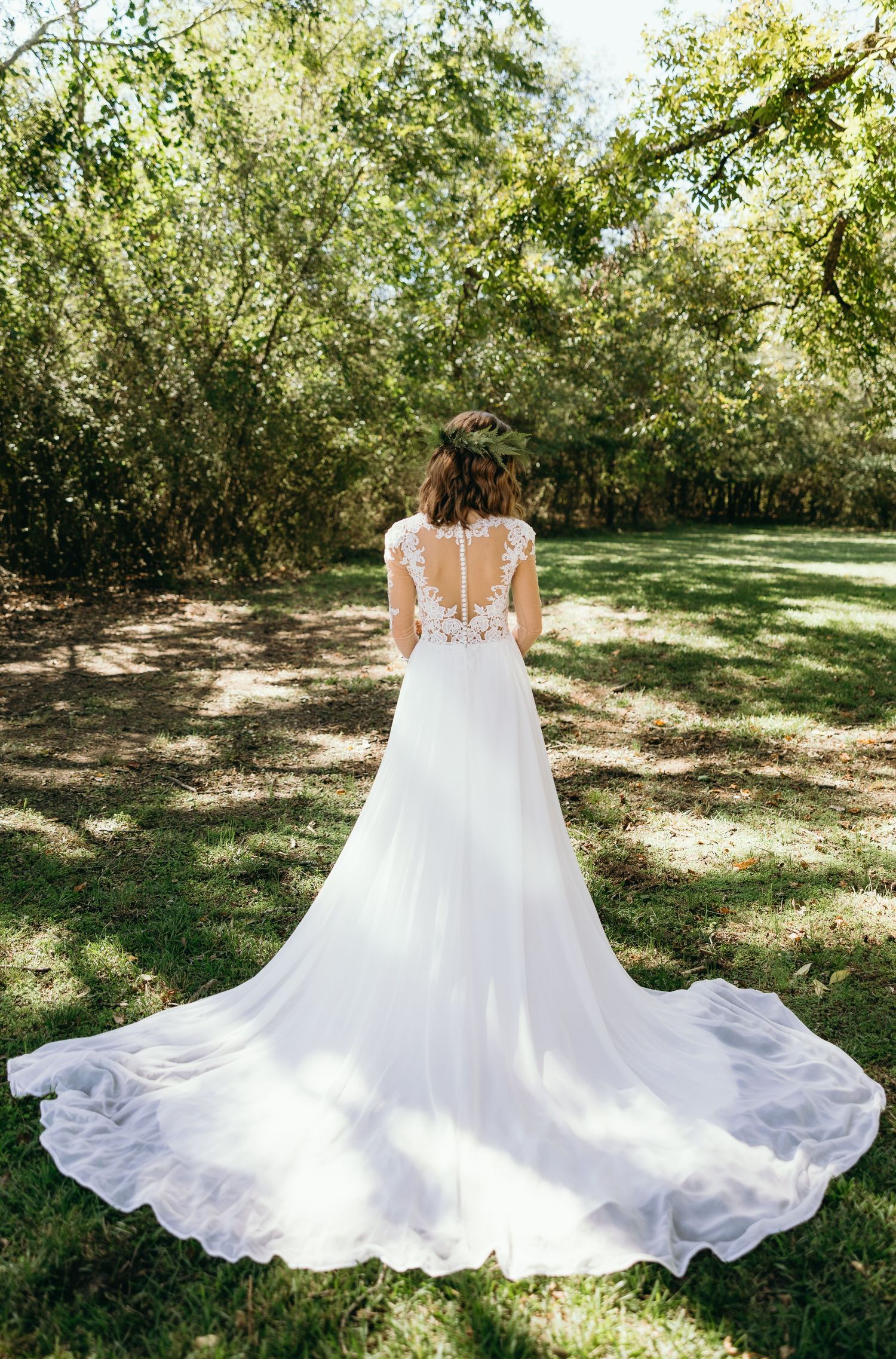 Fine Art Bridal Portrait of the back of a bride's luxury wedding gown with a long train, captured in natural outdoor light.