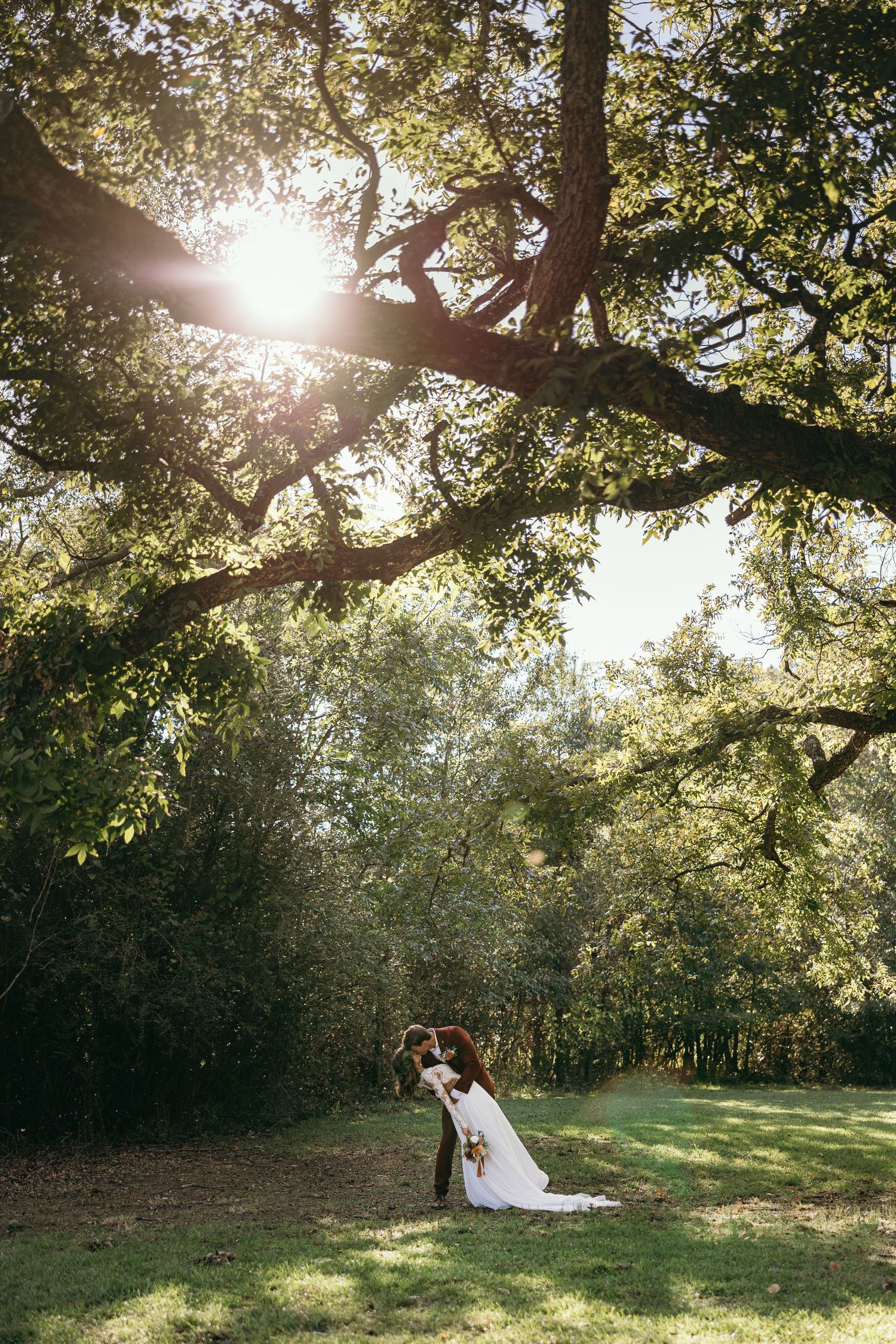 Artistic golden hour wedding portrait of the couple embracing under a massive oak tree at an outdoor wedding venue in Chattanooga, TN.