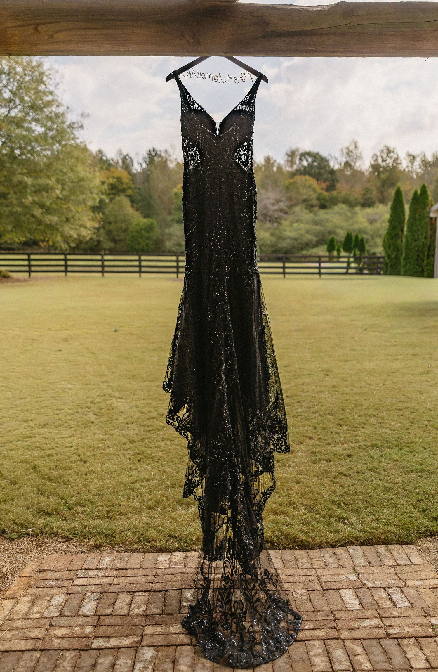 Unique Fine Art wedding dress detail shot of a bride in a black designer gown hanging outdoors before the ceremony.