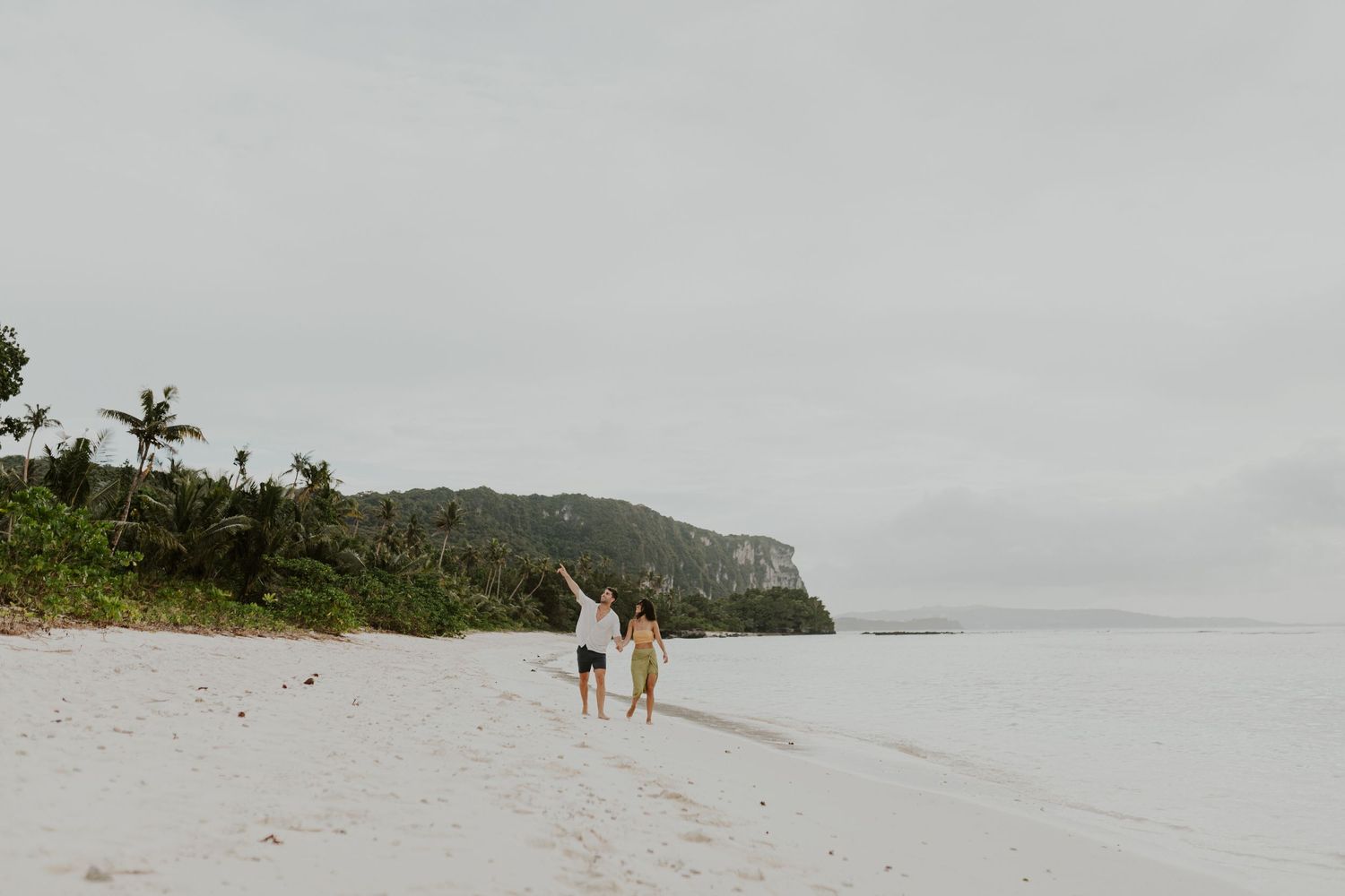 Fine Art photography of a newlywed couple walking along a vast pristine white sand beach. Destination elopement portfolio